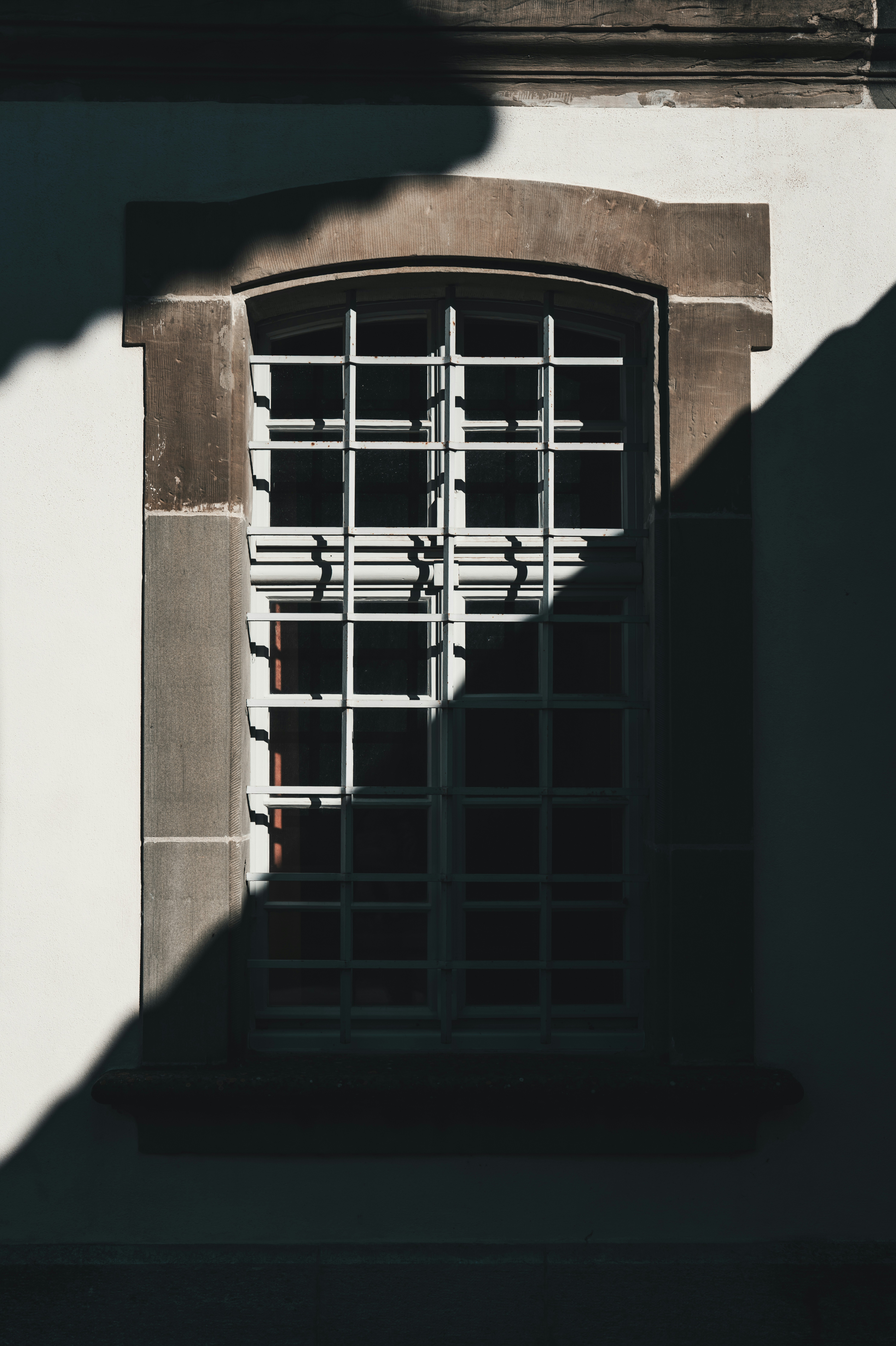 A window with a metal grid frame set in a stone wall