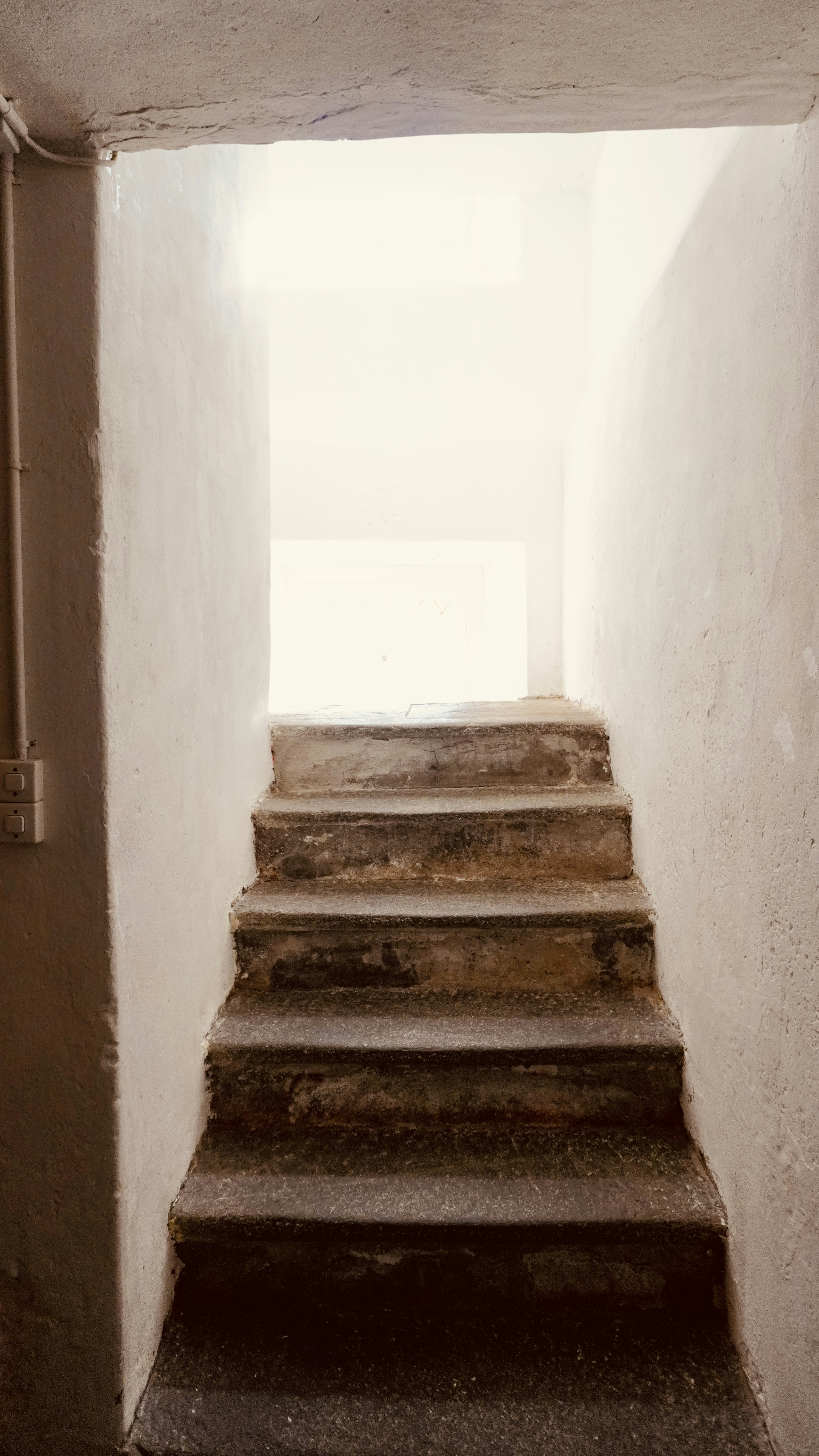 Stone stairs leading up to a bright doorway between white walls