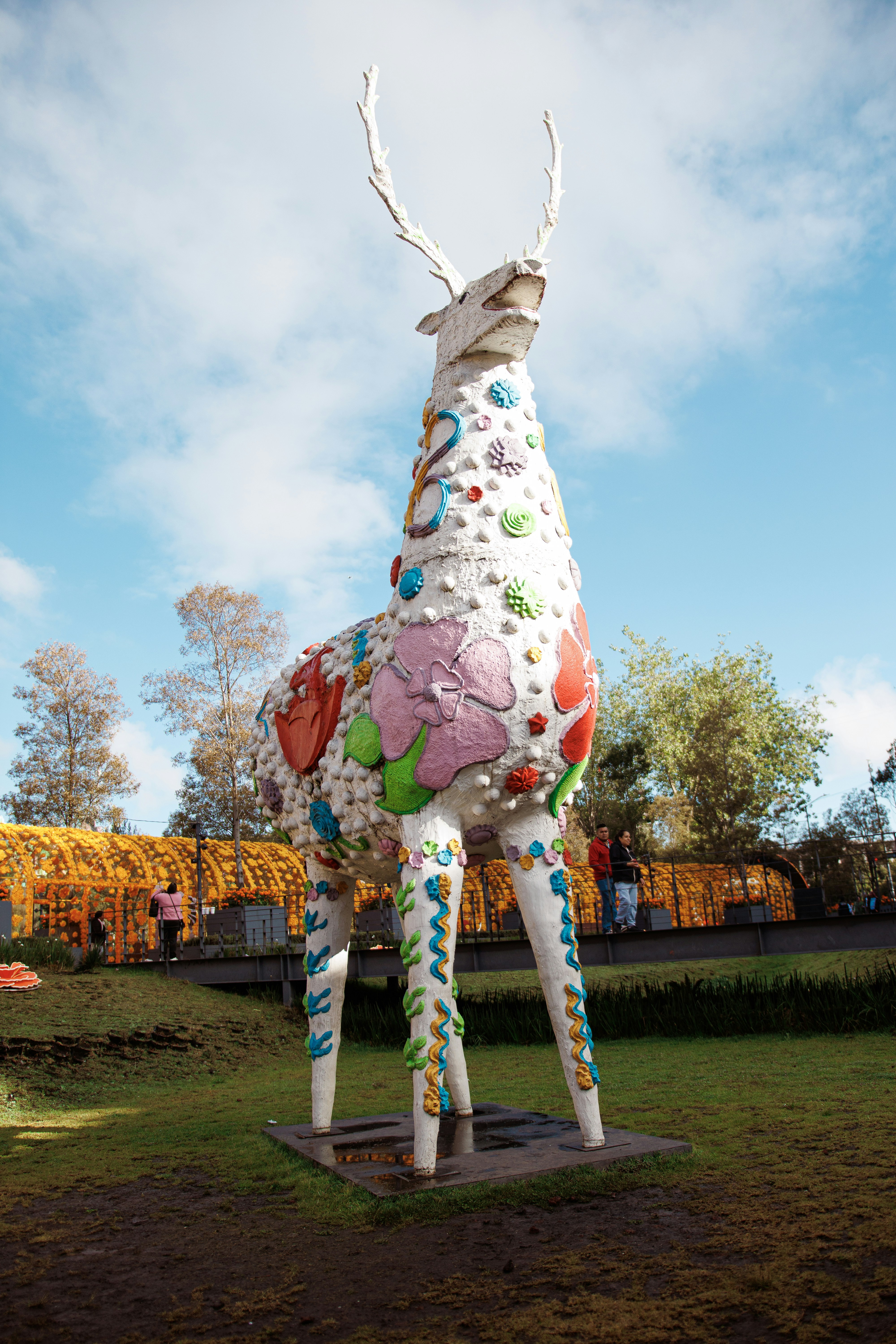 A large white deer sculpture decorated with colorful floral patterns in a park