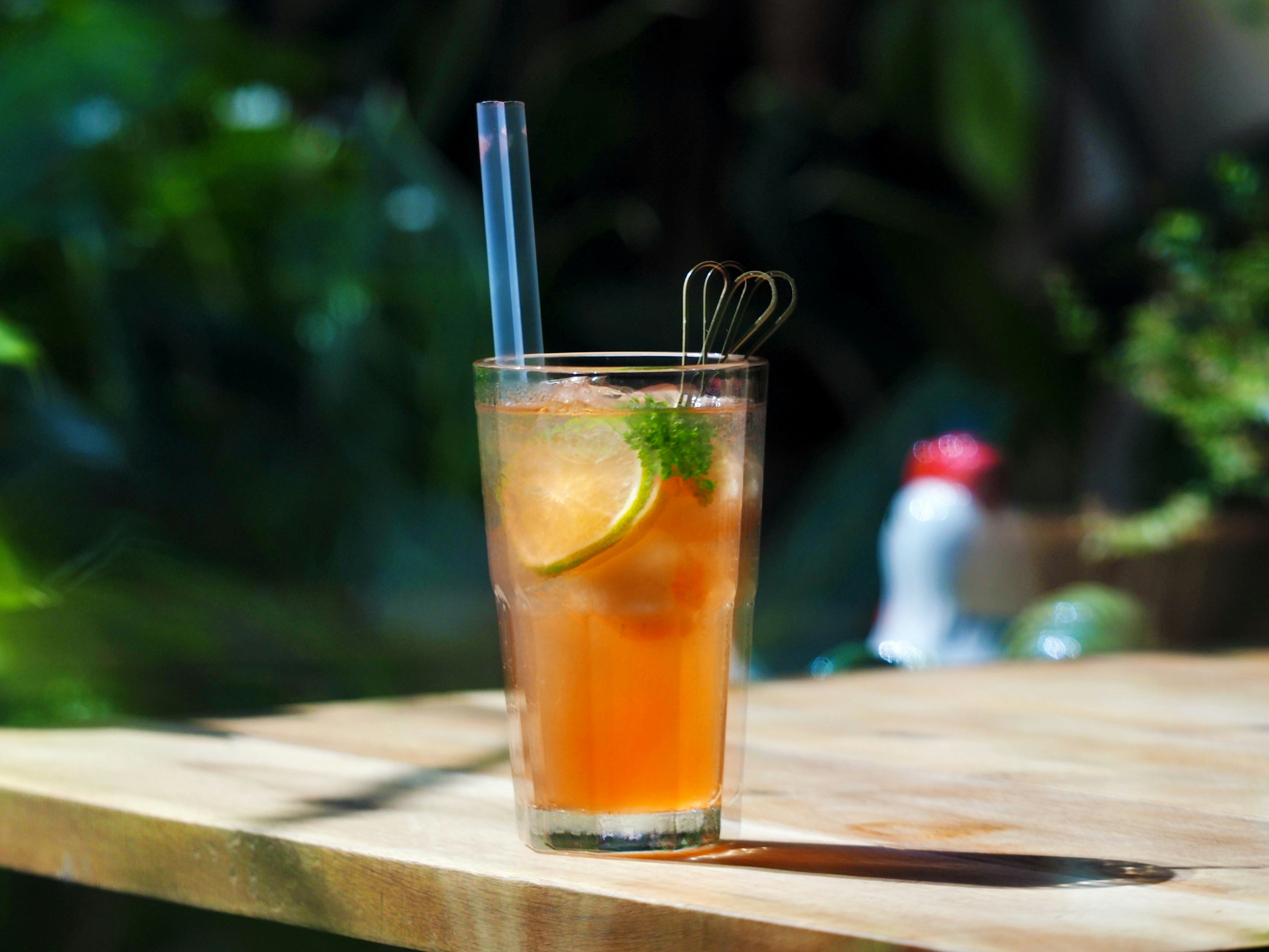 Un cocktail all'arancia con una fetta di lime e paglia su un tavolo di legno