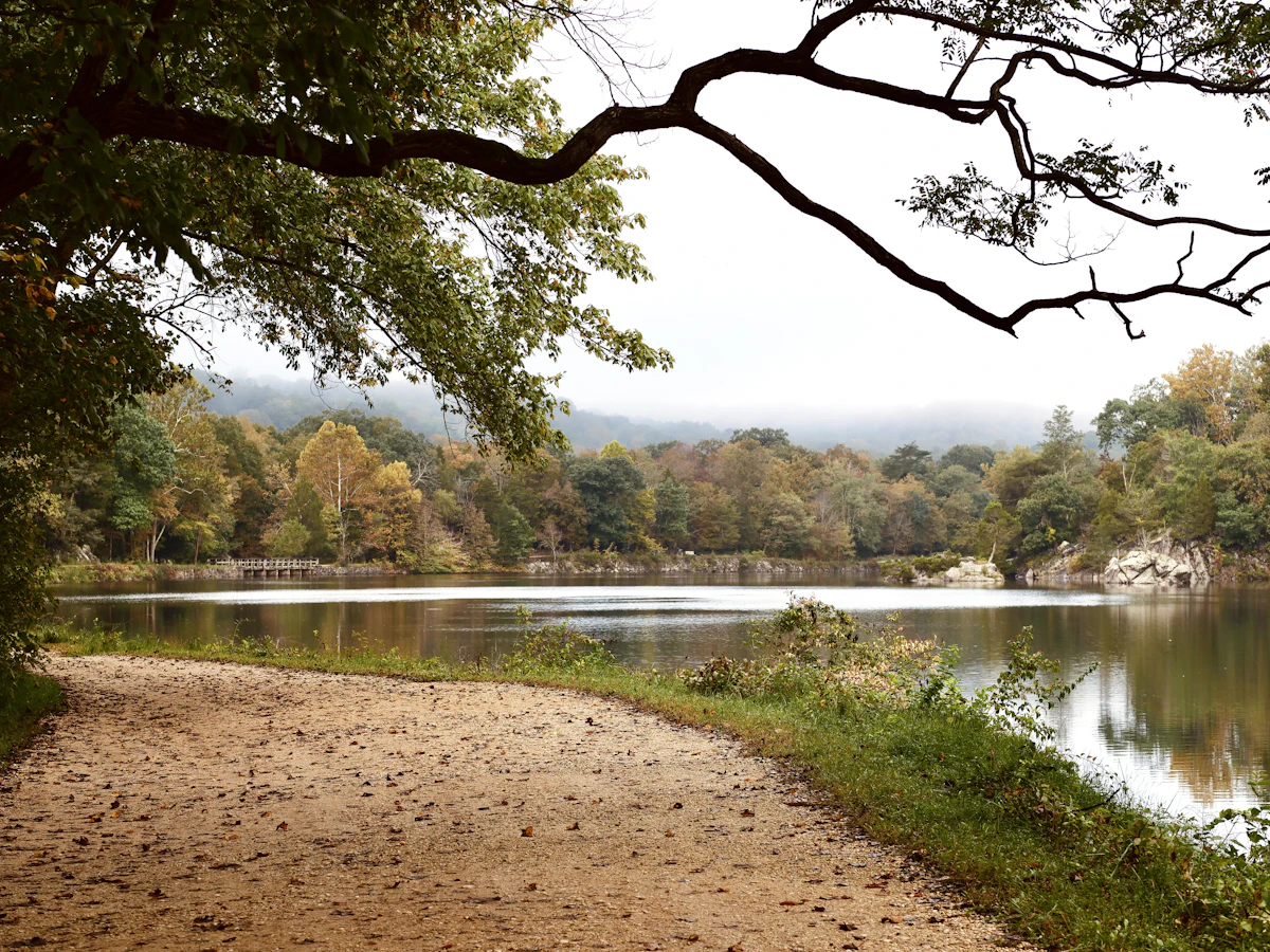 A dirt path beside calm water and autumn trees at Great Falls Park in Potomac, Maryland