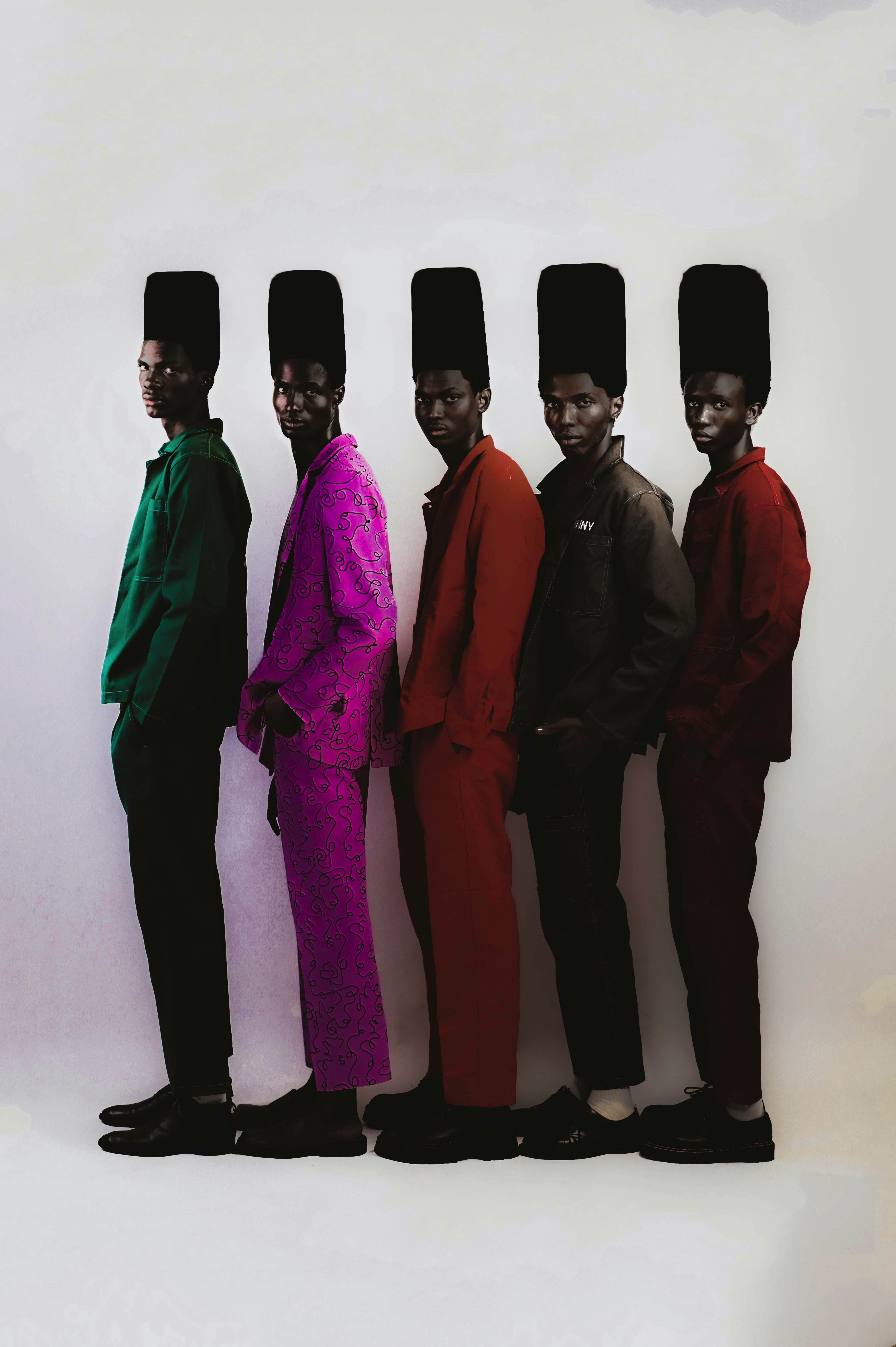 Five men in colorful suits and tall black hats against a white background