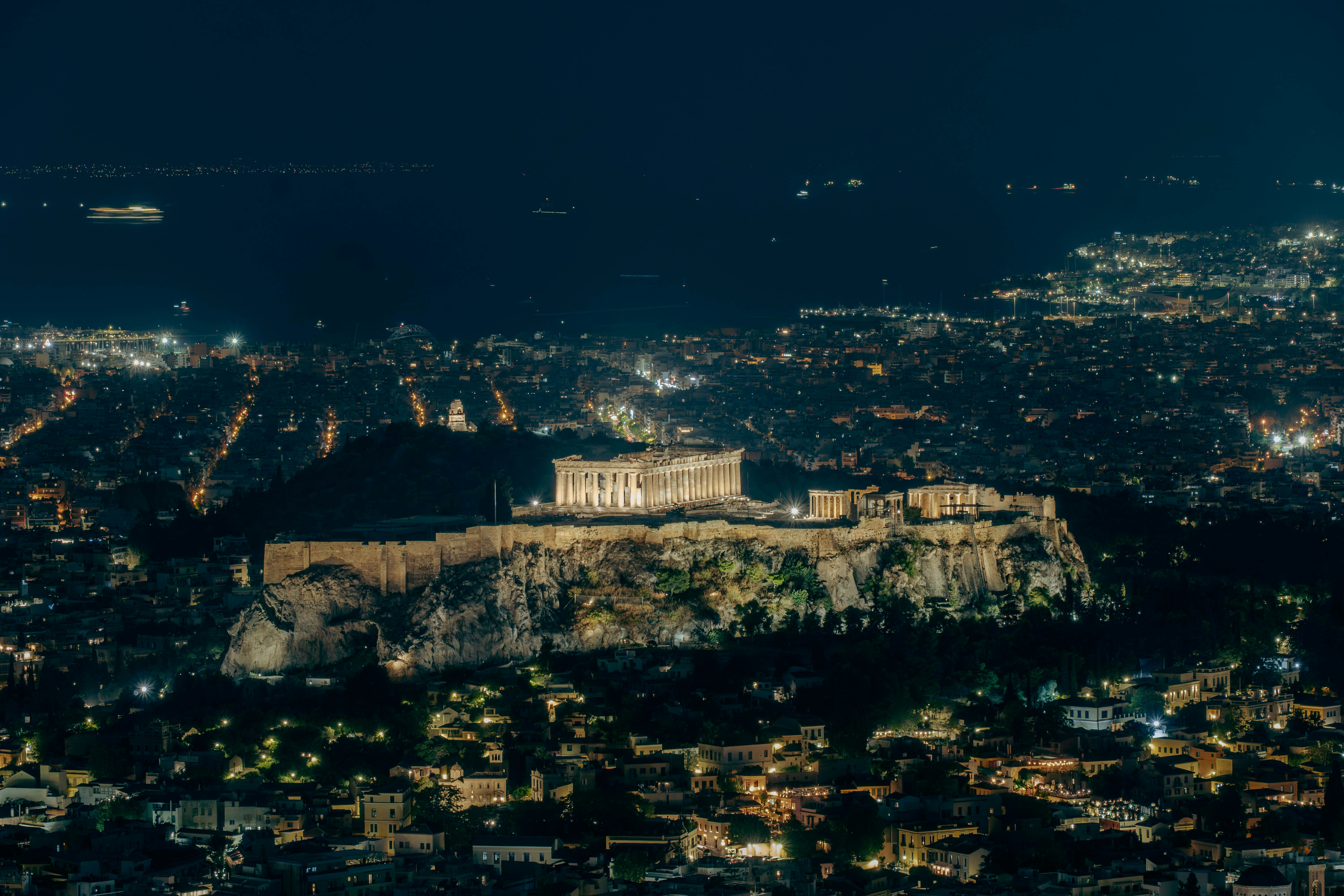 The illuminated Parthenon on the Acropolis hill overlooking the city of Athens at night