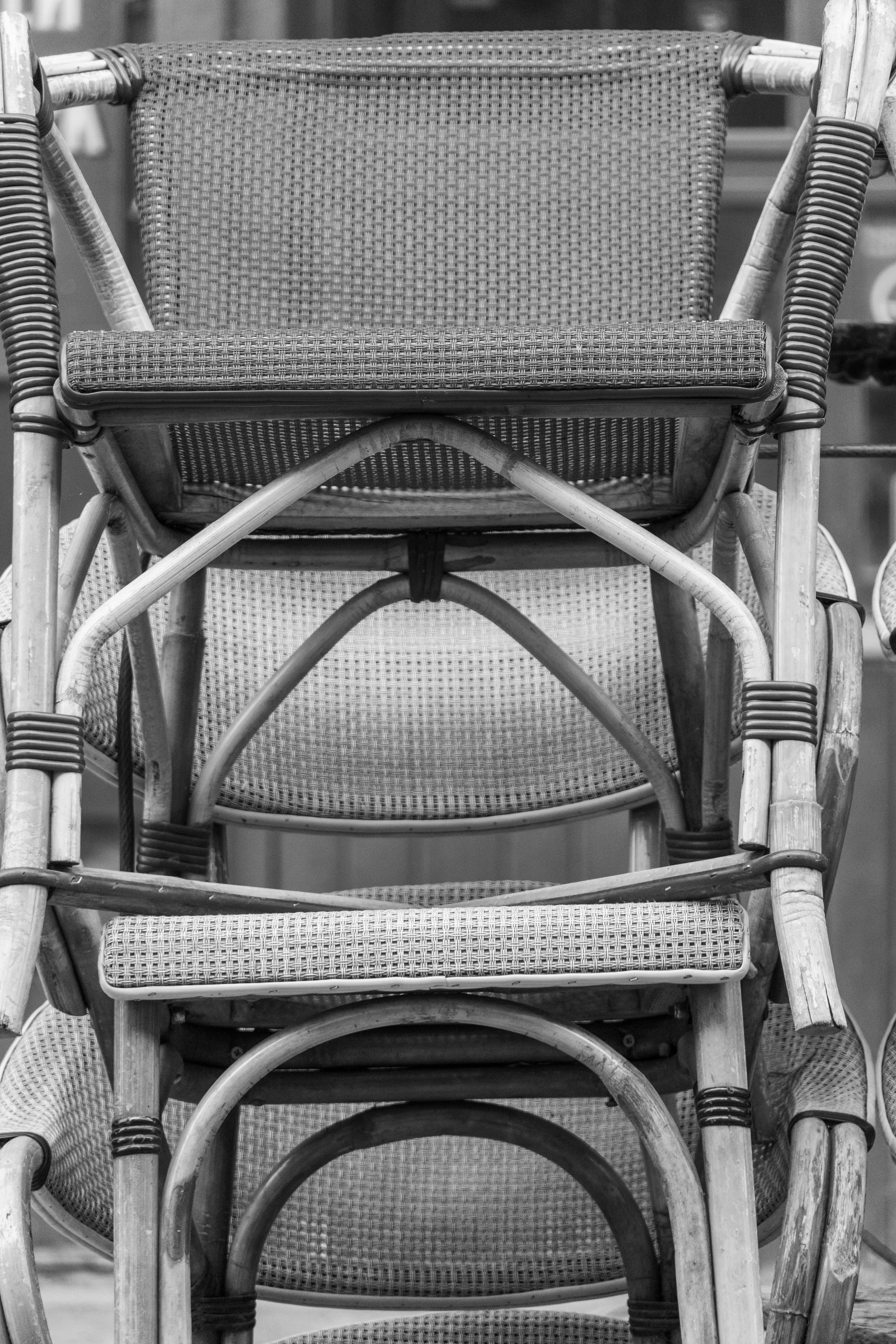 A stack of woven rattan bistro chairs in black and white