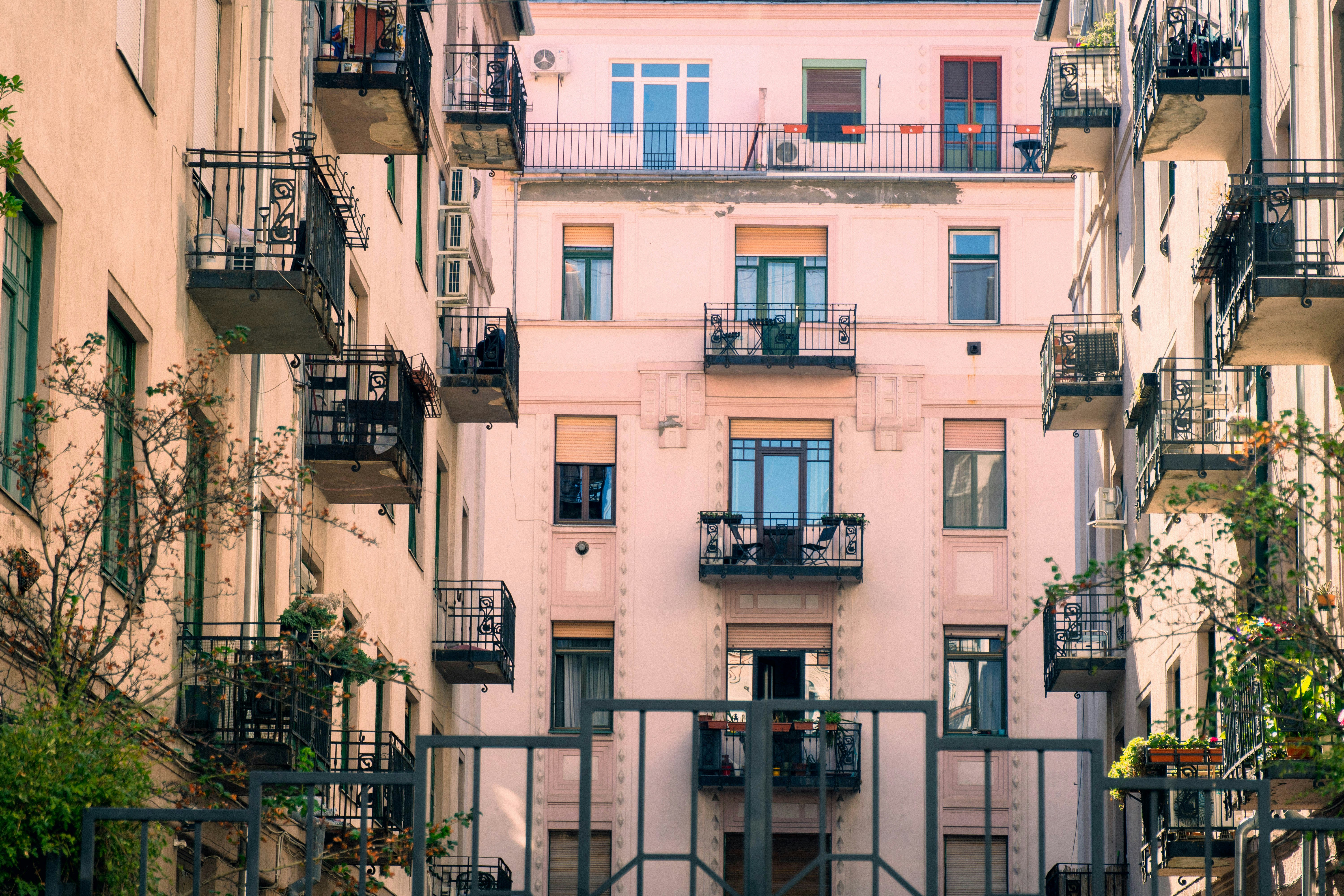 A pink apartment building with many small black metal balconies and windows