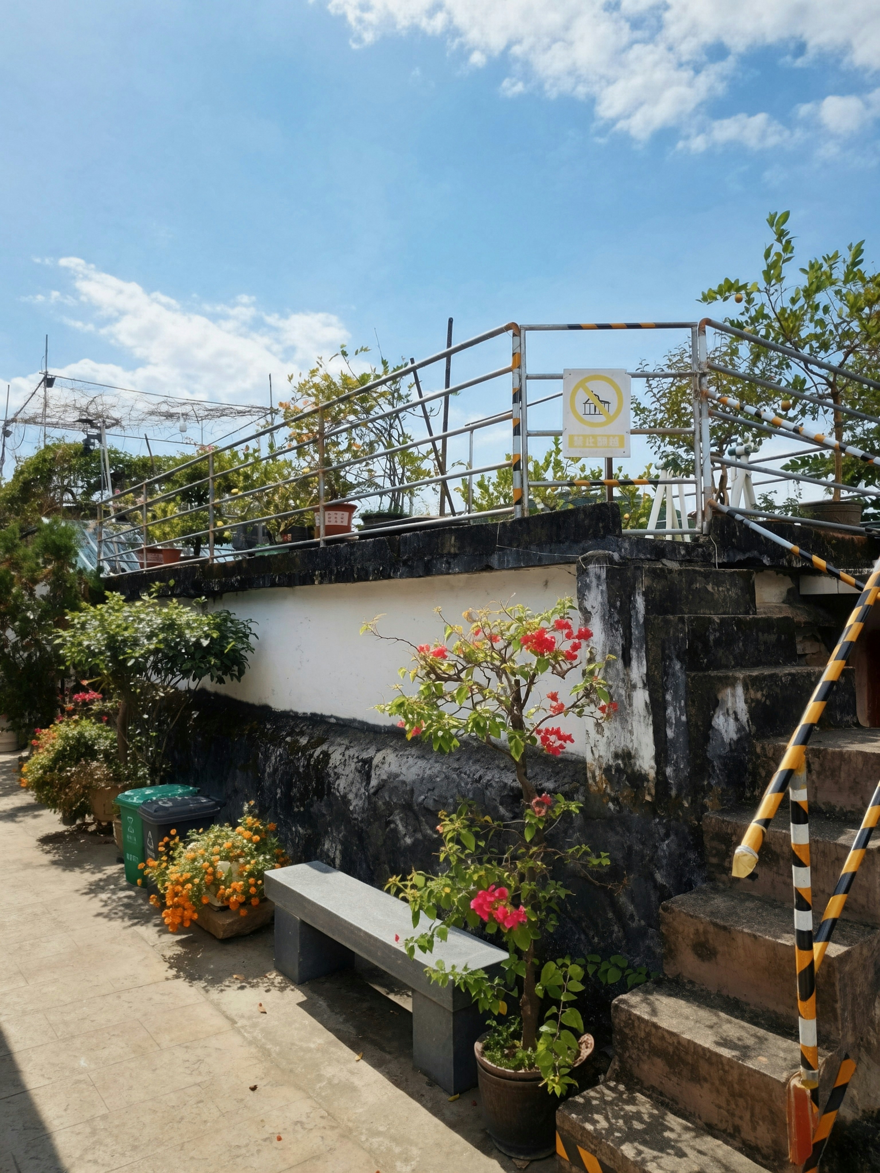A stone staircase with yellow and black striped railings leading to a rooftop garden