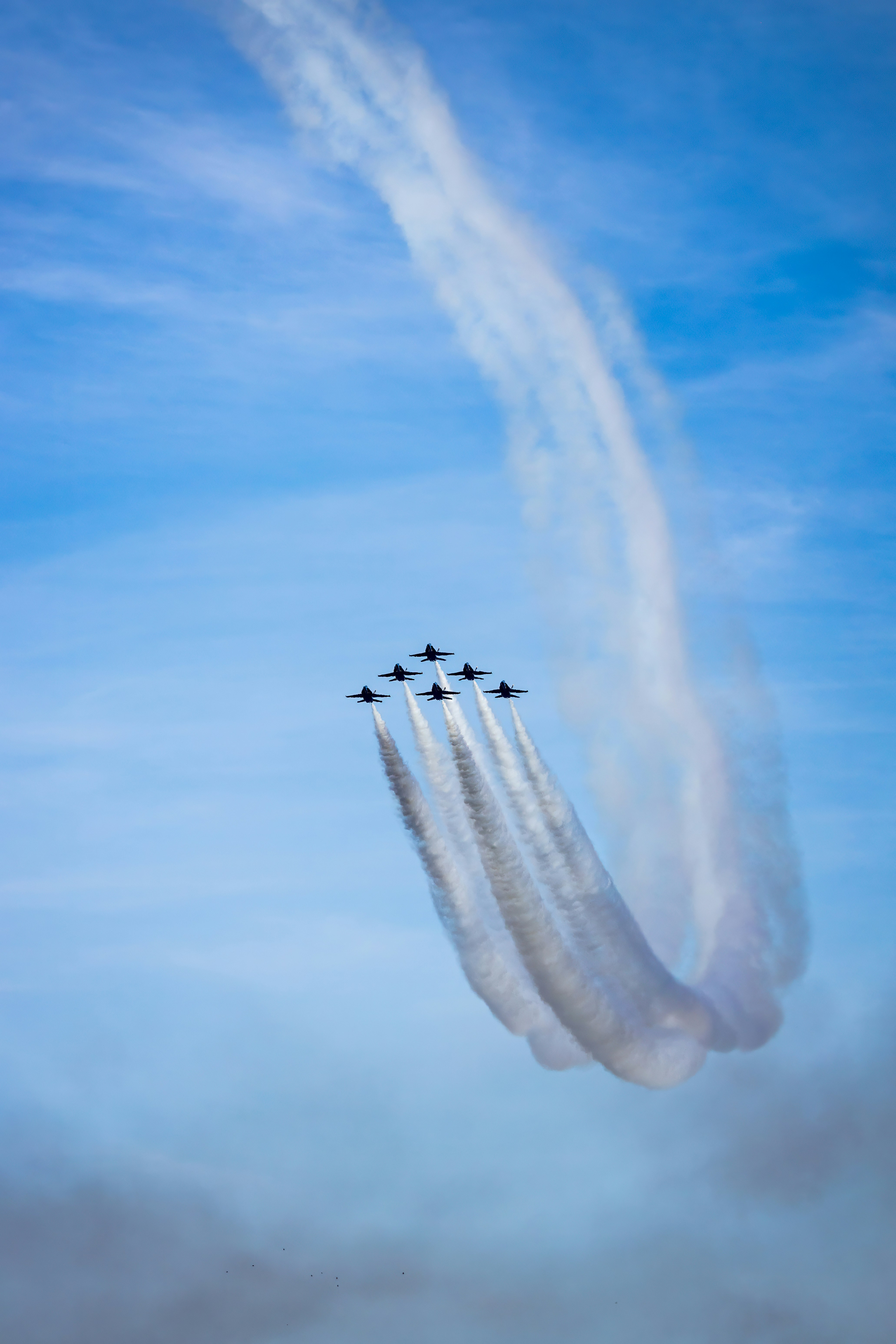 Six fighter jets flying in formation leaving white smoke trails against a blue sky