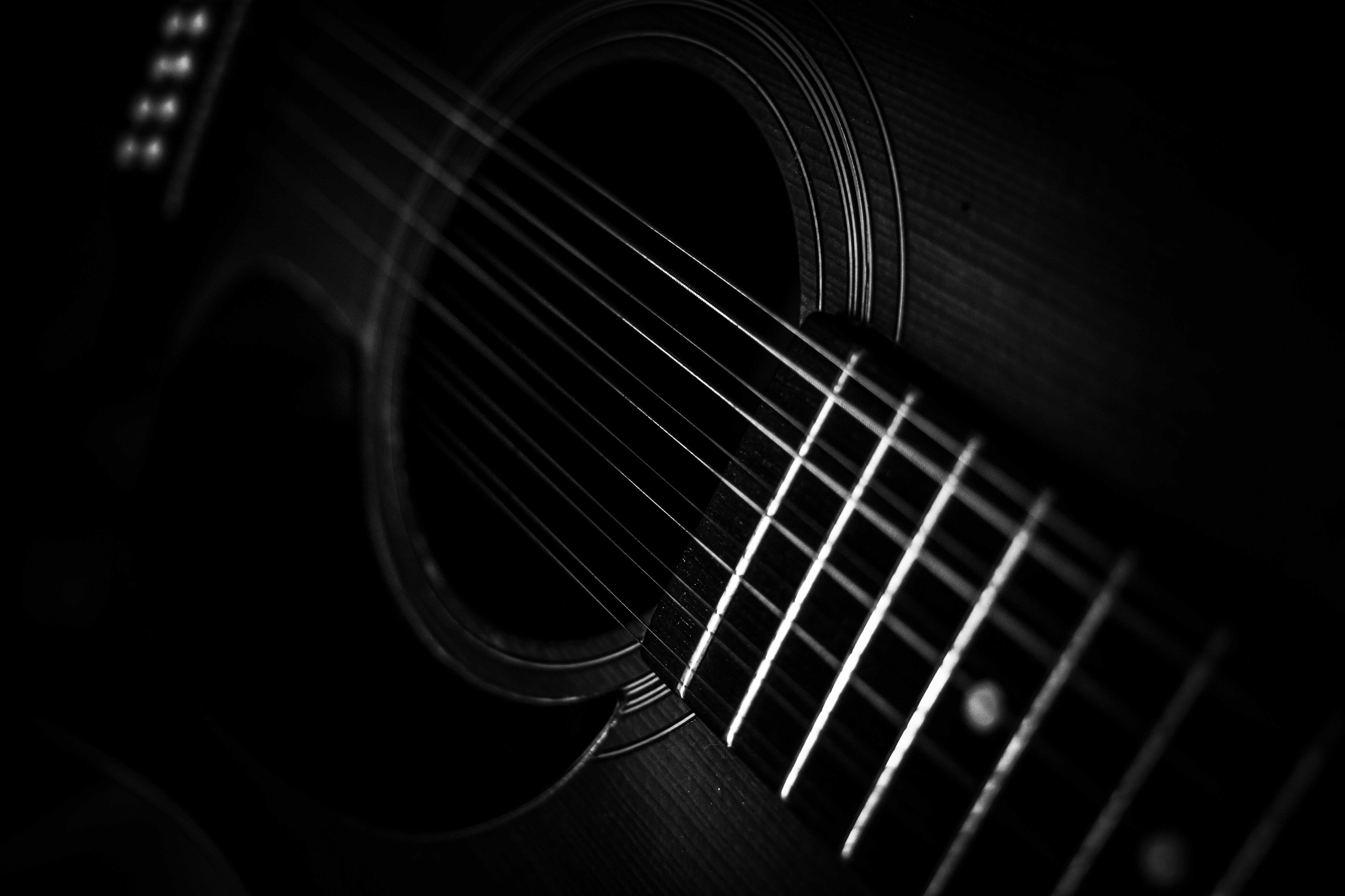 A black and white close-up of acoustic guitar strings over the sound hole
