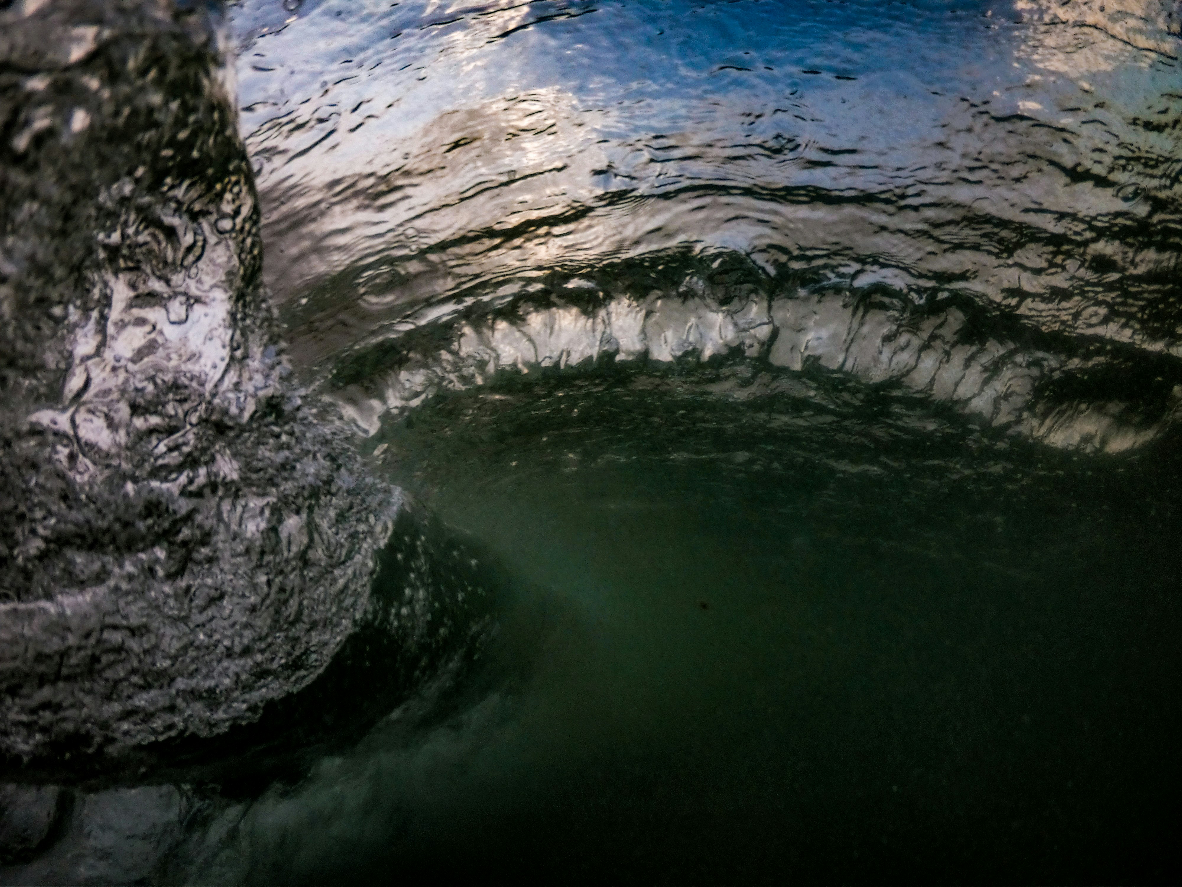 Underwater view of a curling wave with light reflecting on the surface