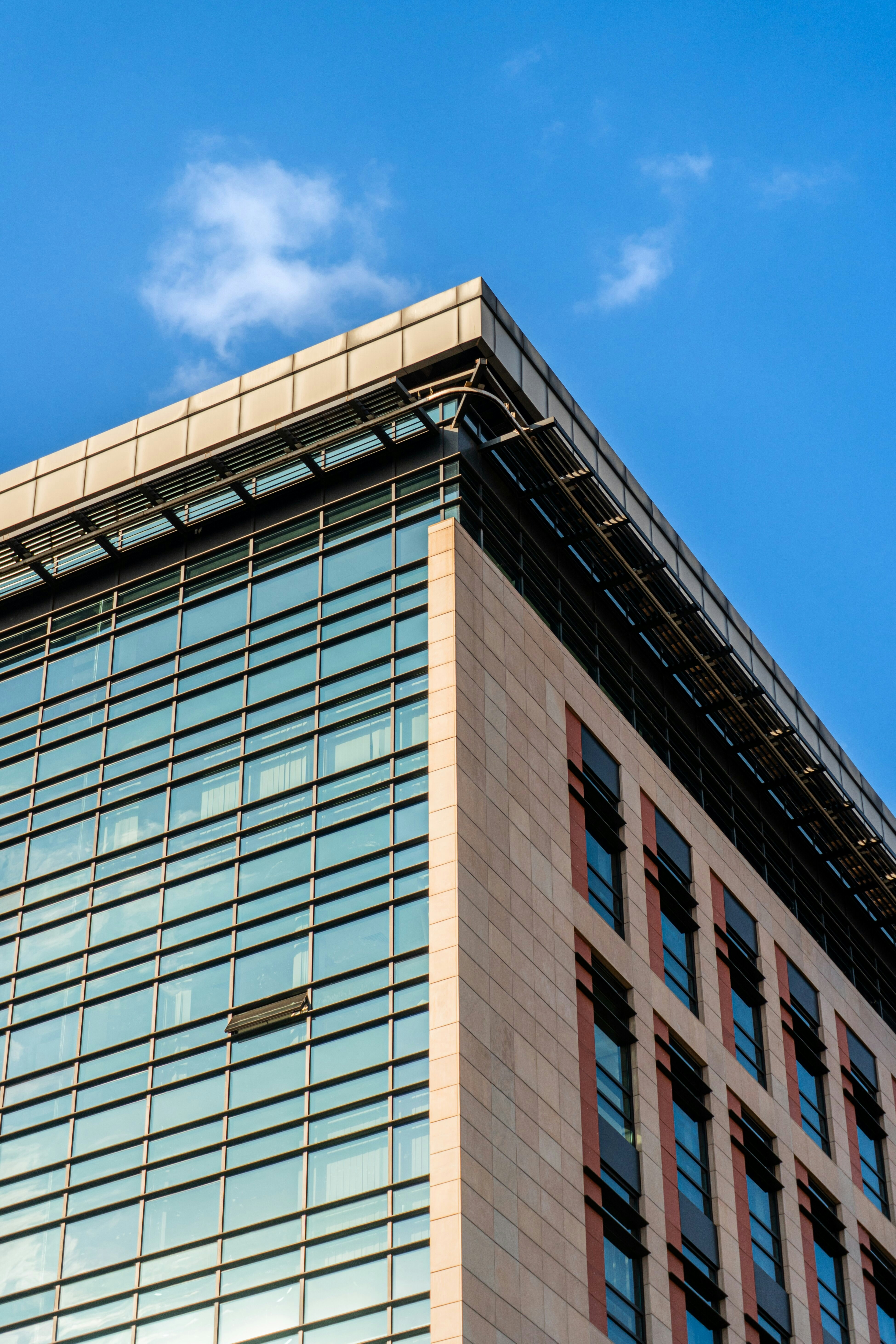 A corner of a modern office building with glass windows and stone panels