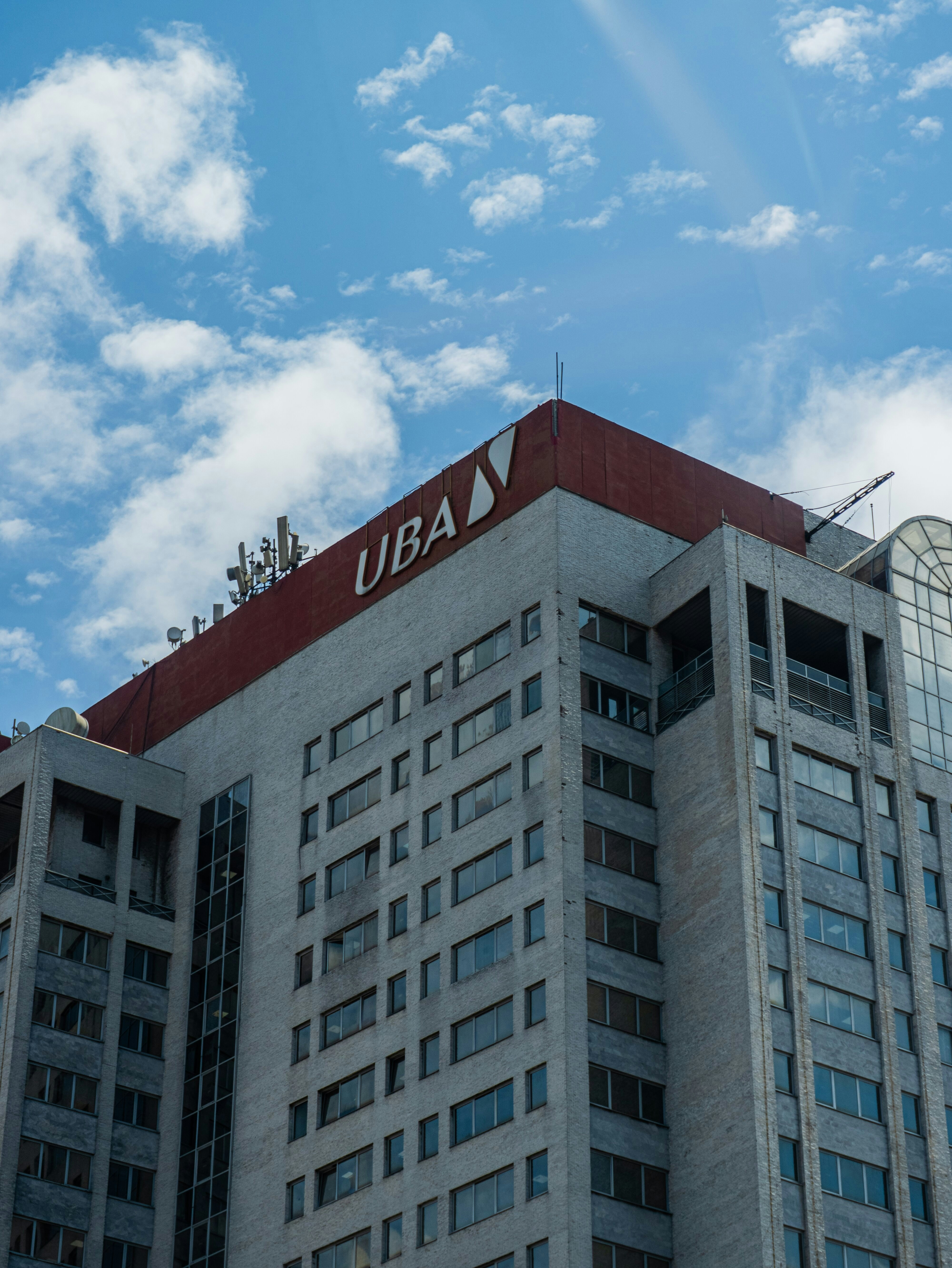 A tall grey office building with a red roof and UBA signage