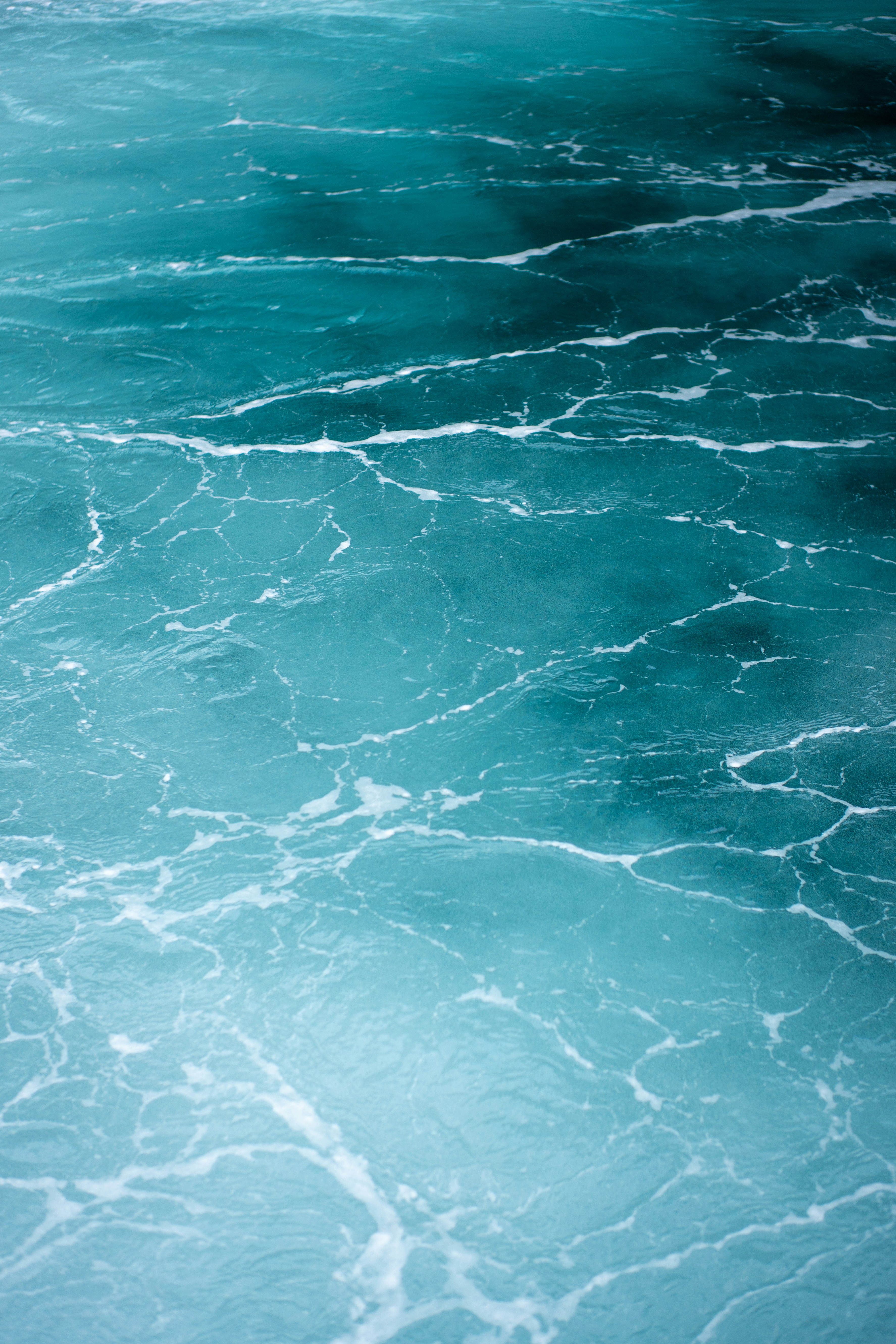 White foam patterns on the surface of deep turquoise ocean water
