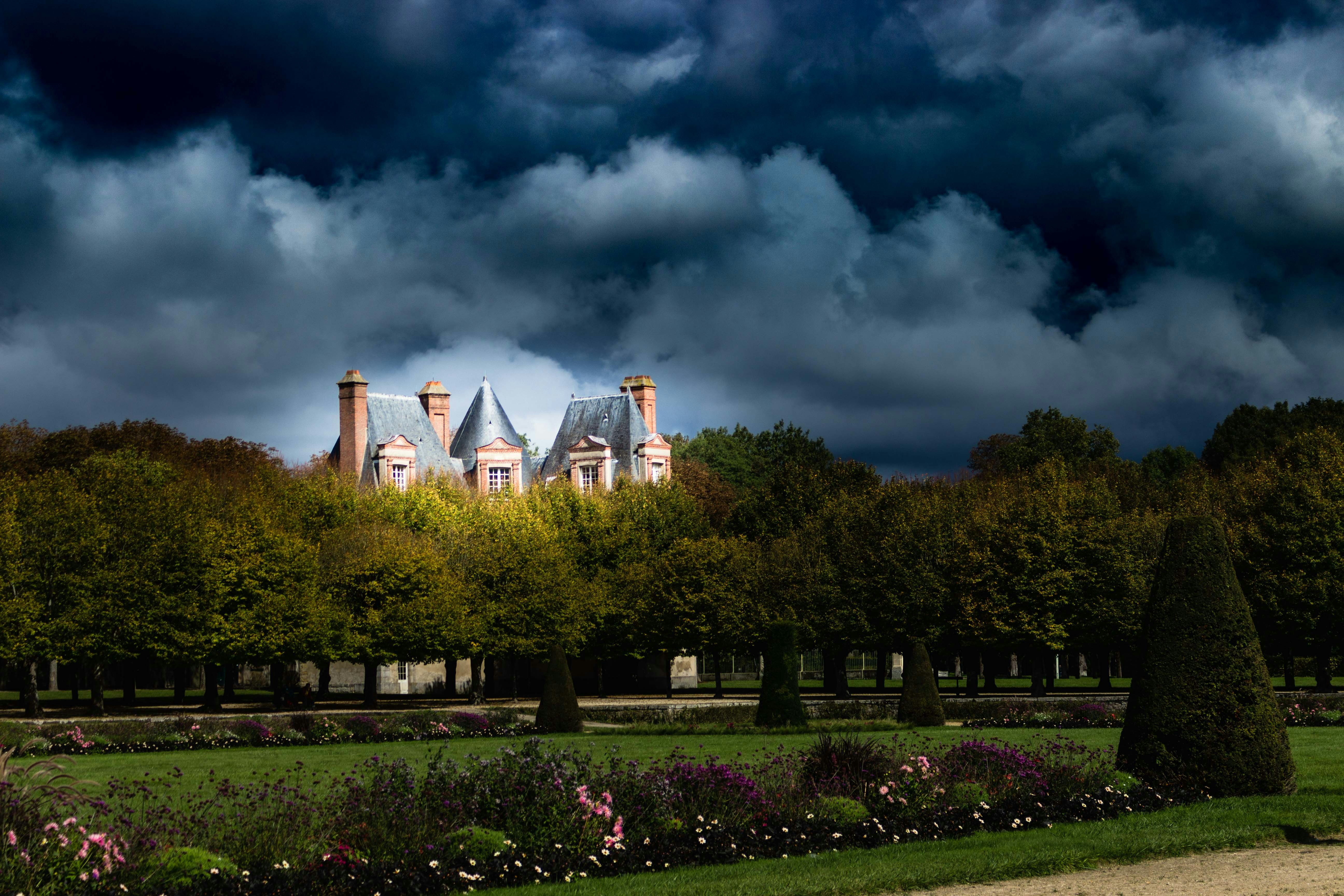Chateau behind trees under stormy sky - Free Photo on Unsplash