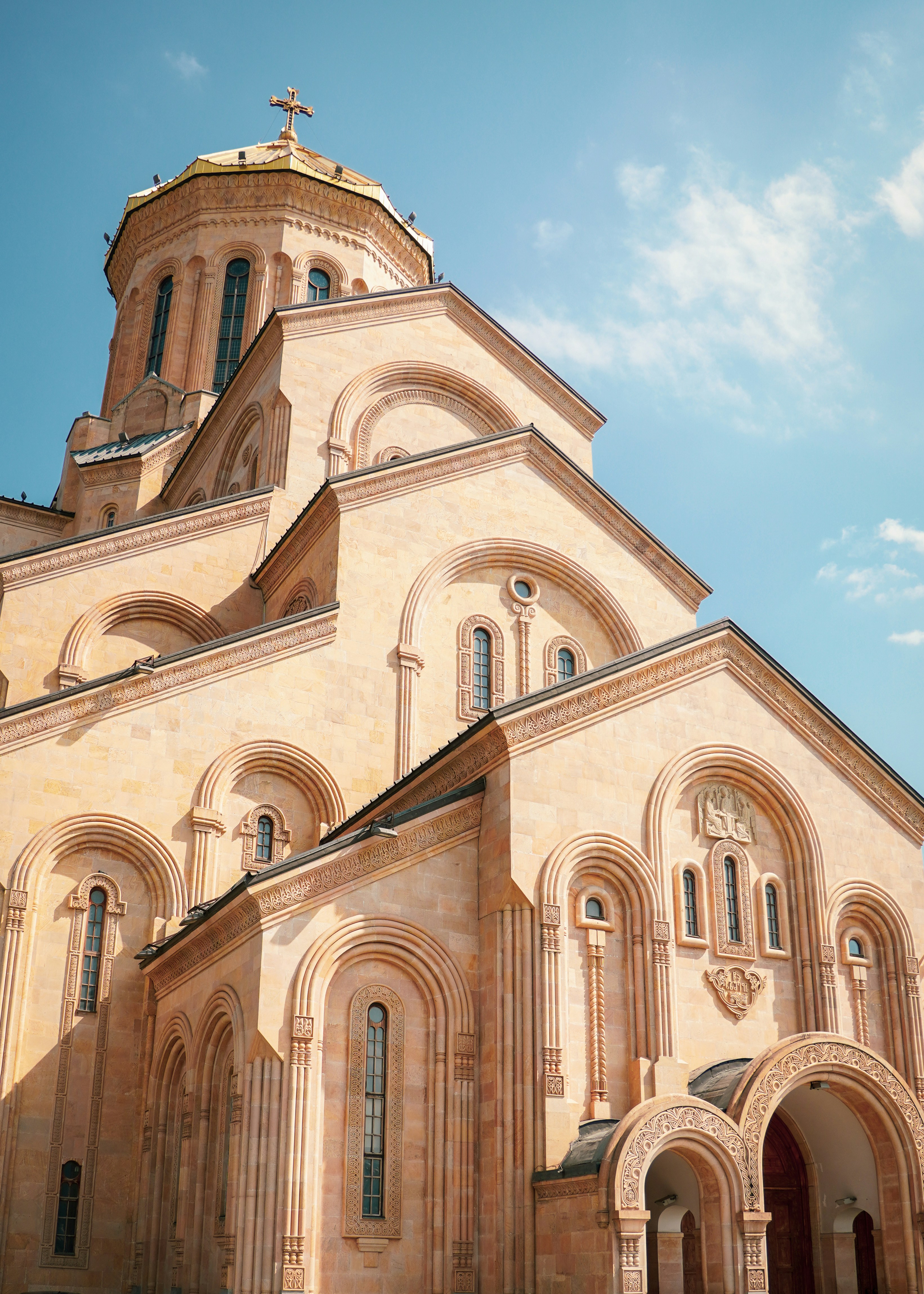 The Holy Trinity Cathedral of Tbilisi with stone arches under a clear blue sky