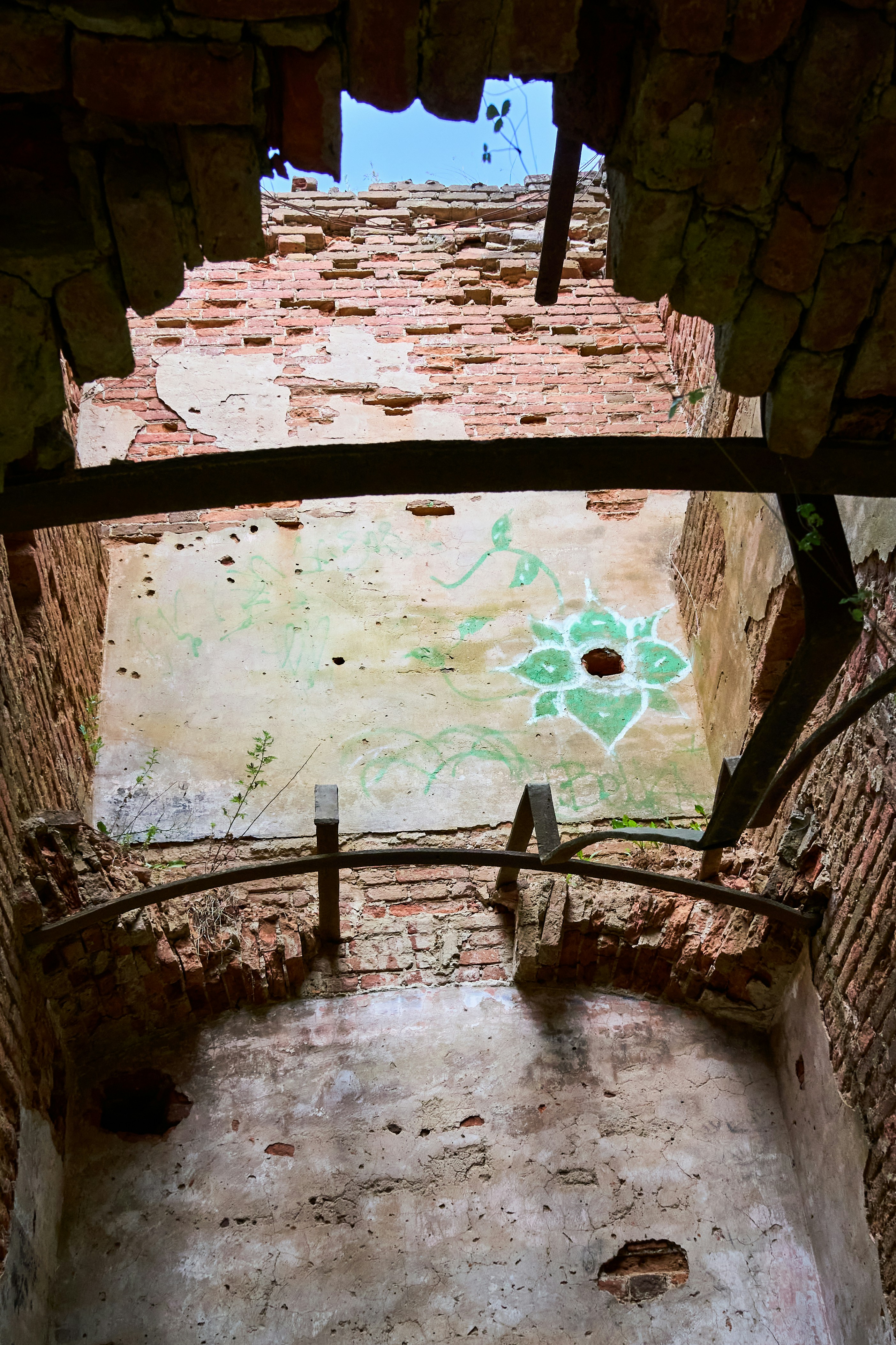 A crumbling brick wall with a green painted flower inside a ruined building