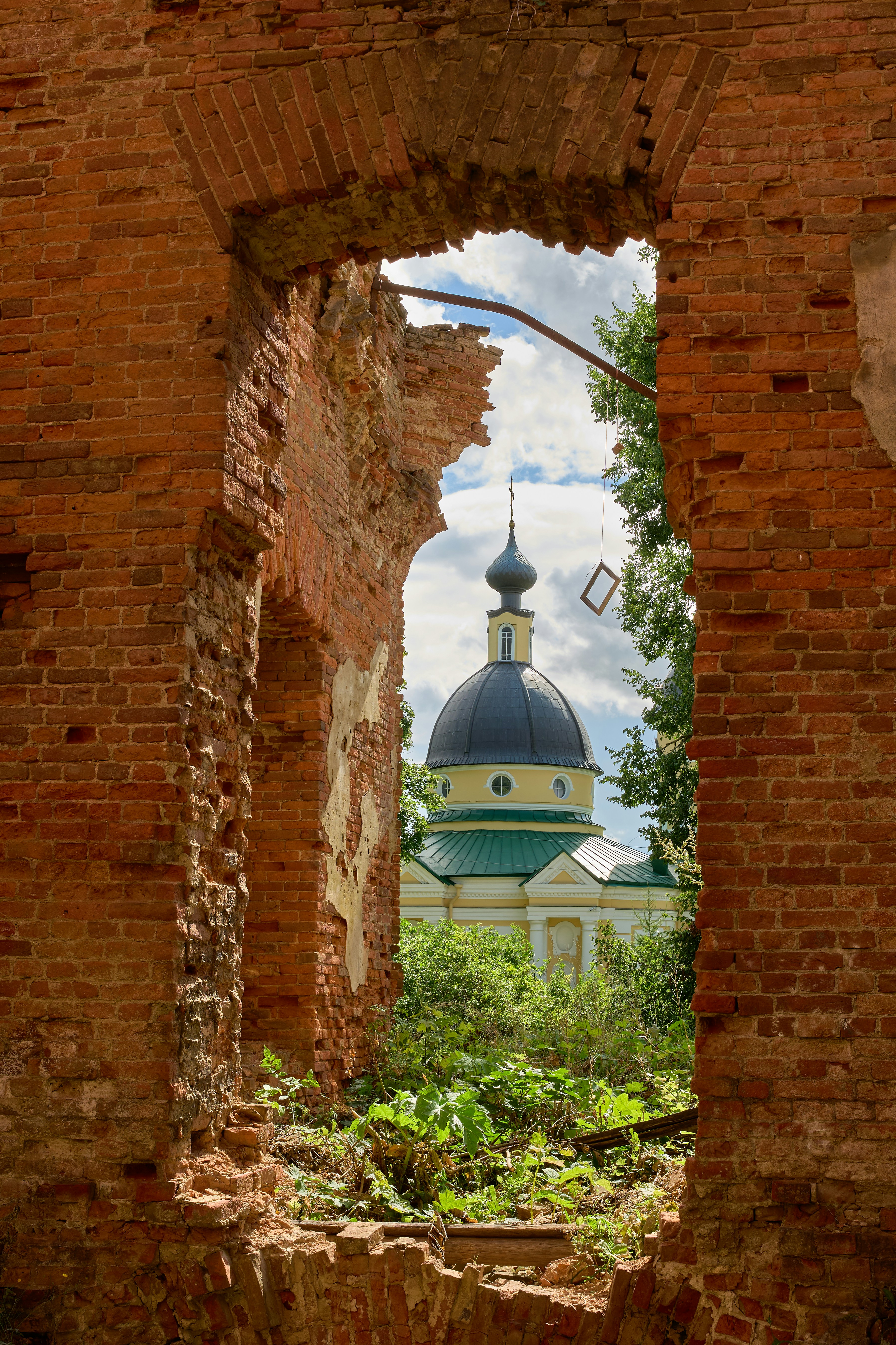 A church dome seen through a large opening in a ruined brick wall