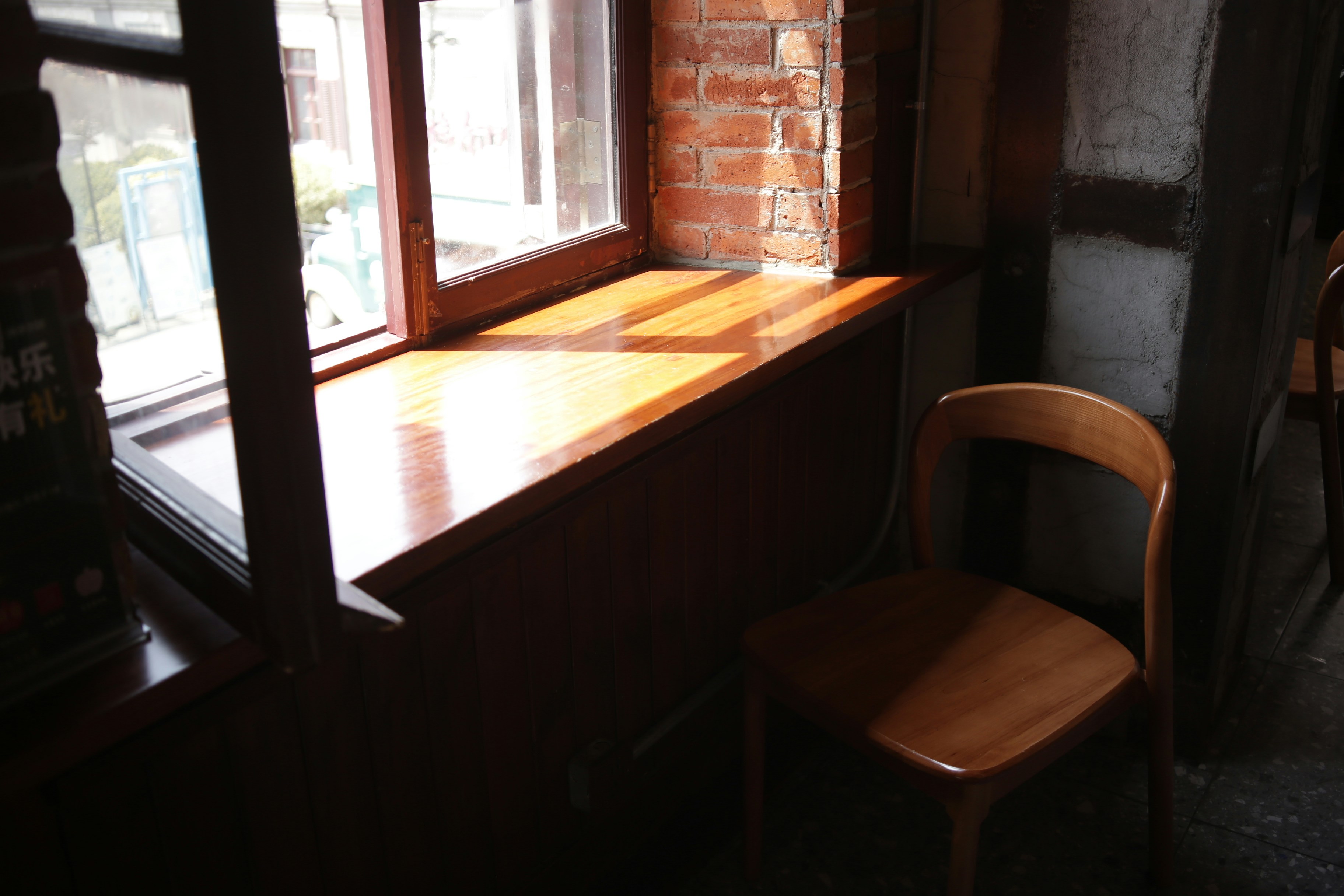 Une chaise en bois à côté d’une fenêtre avec un rebord en bois poli et un mur en briques