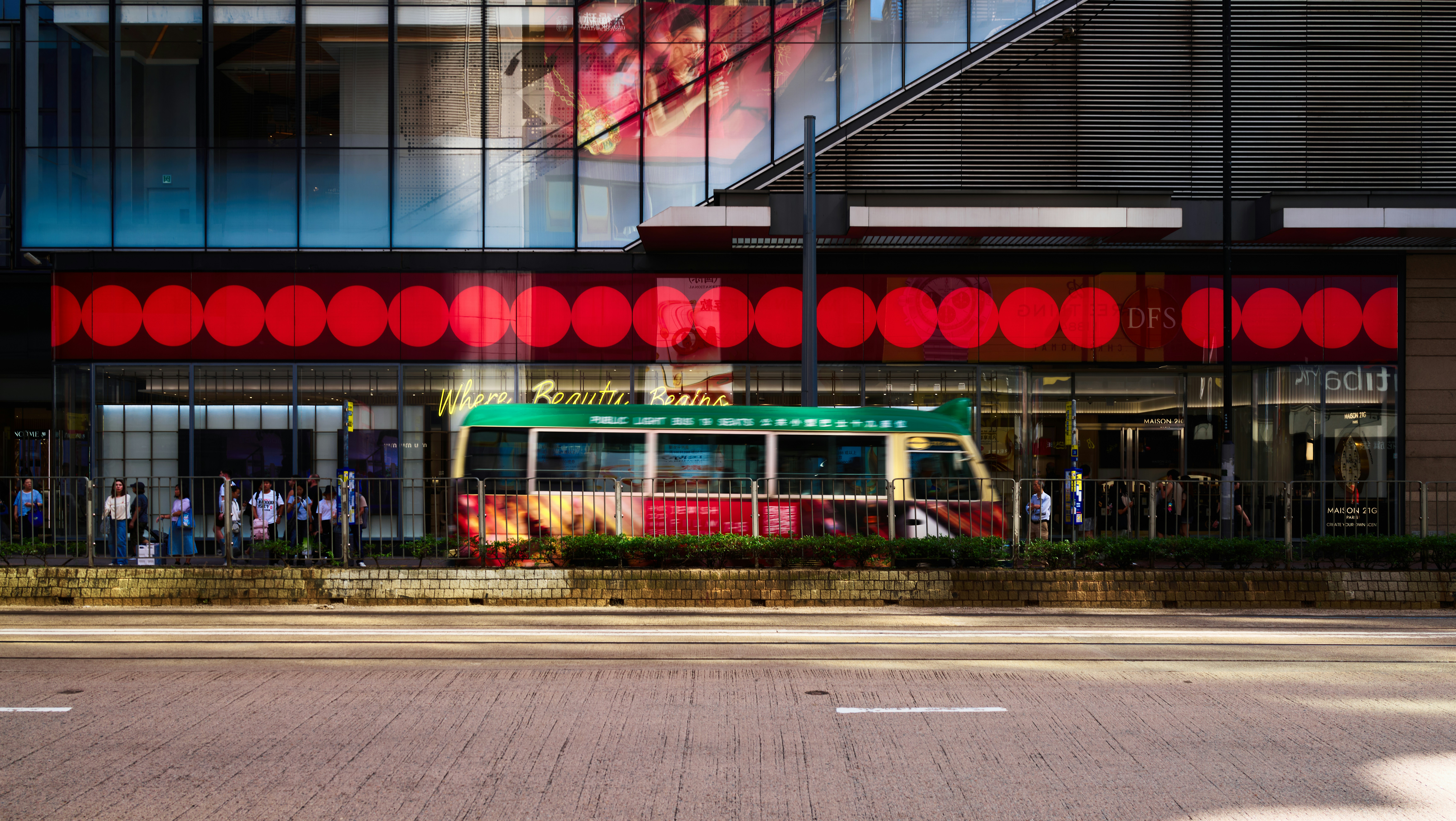 Uma micro-ônibus verde passando por um prédio moderno com sinalização circular vermelha em Hong Kong