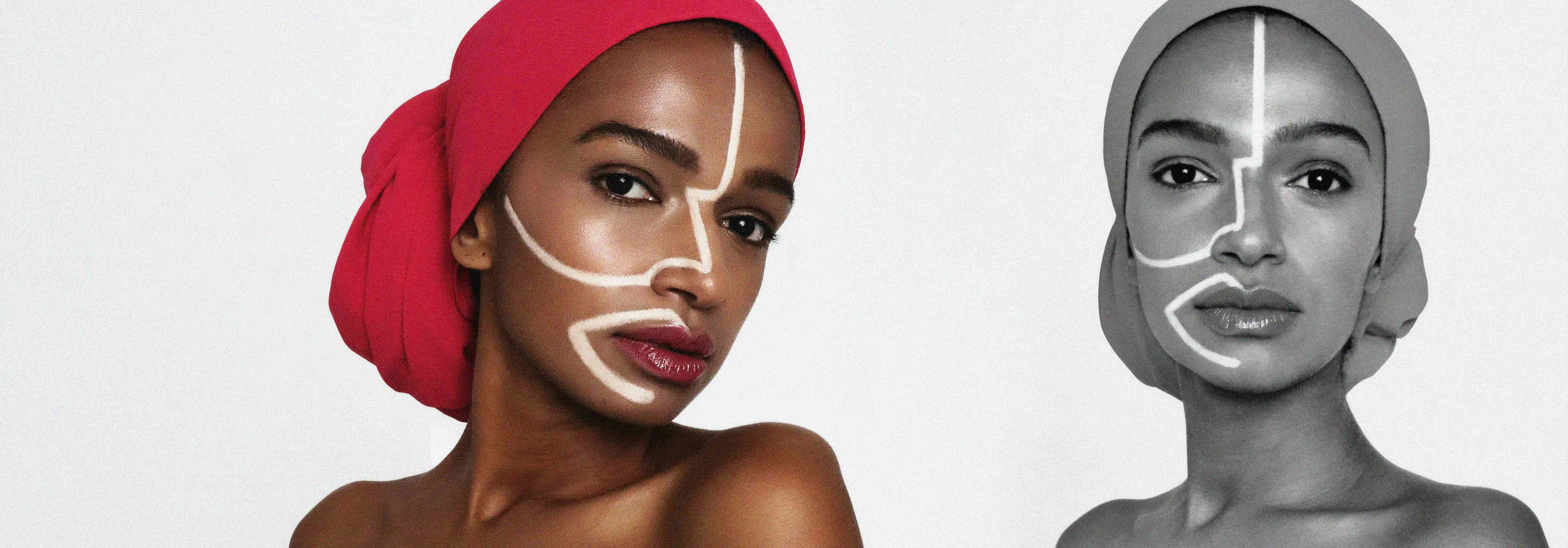 A woman wearing a red headwrap with white face paint lines against white
