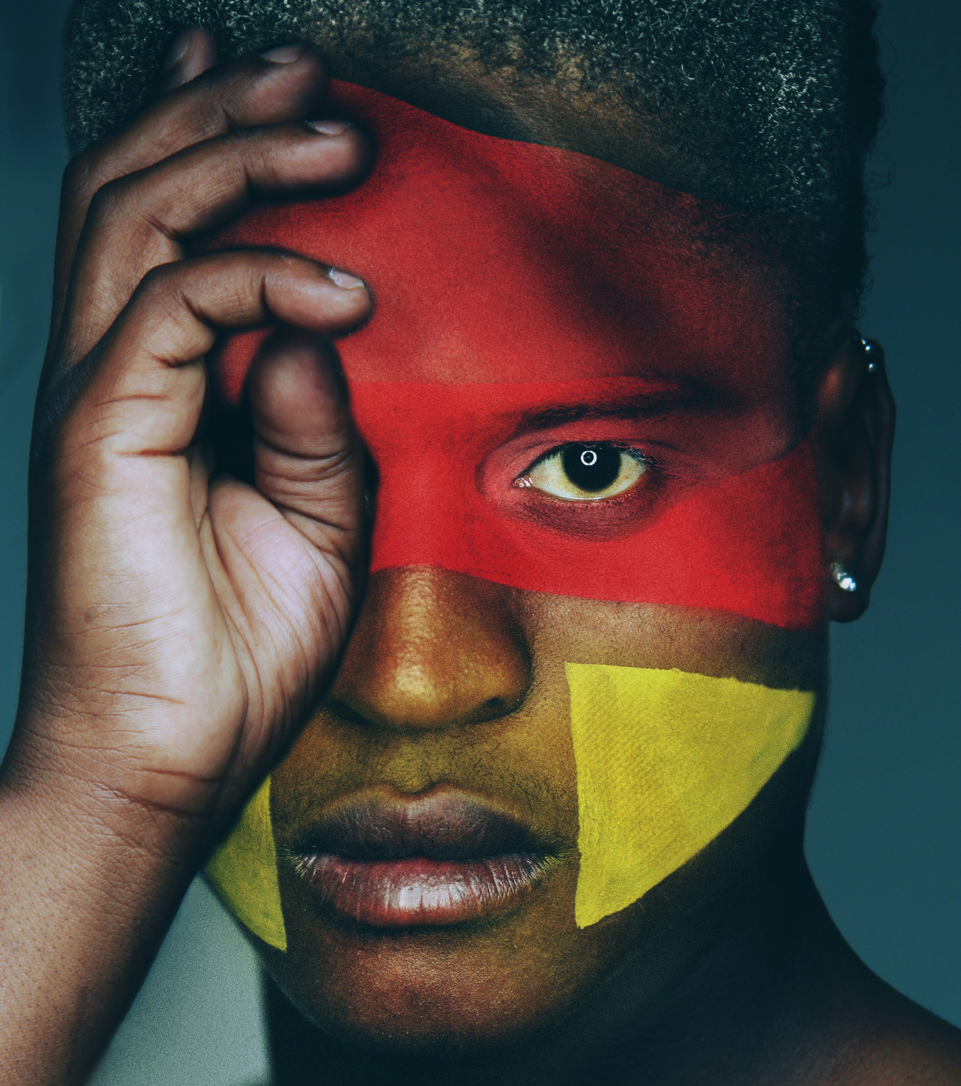 A person with red and yellow face paint covering their eyes and cheeks