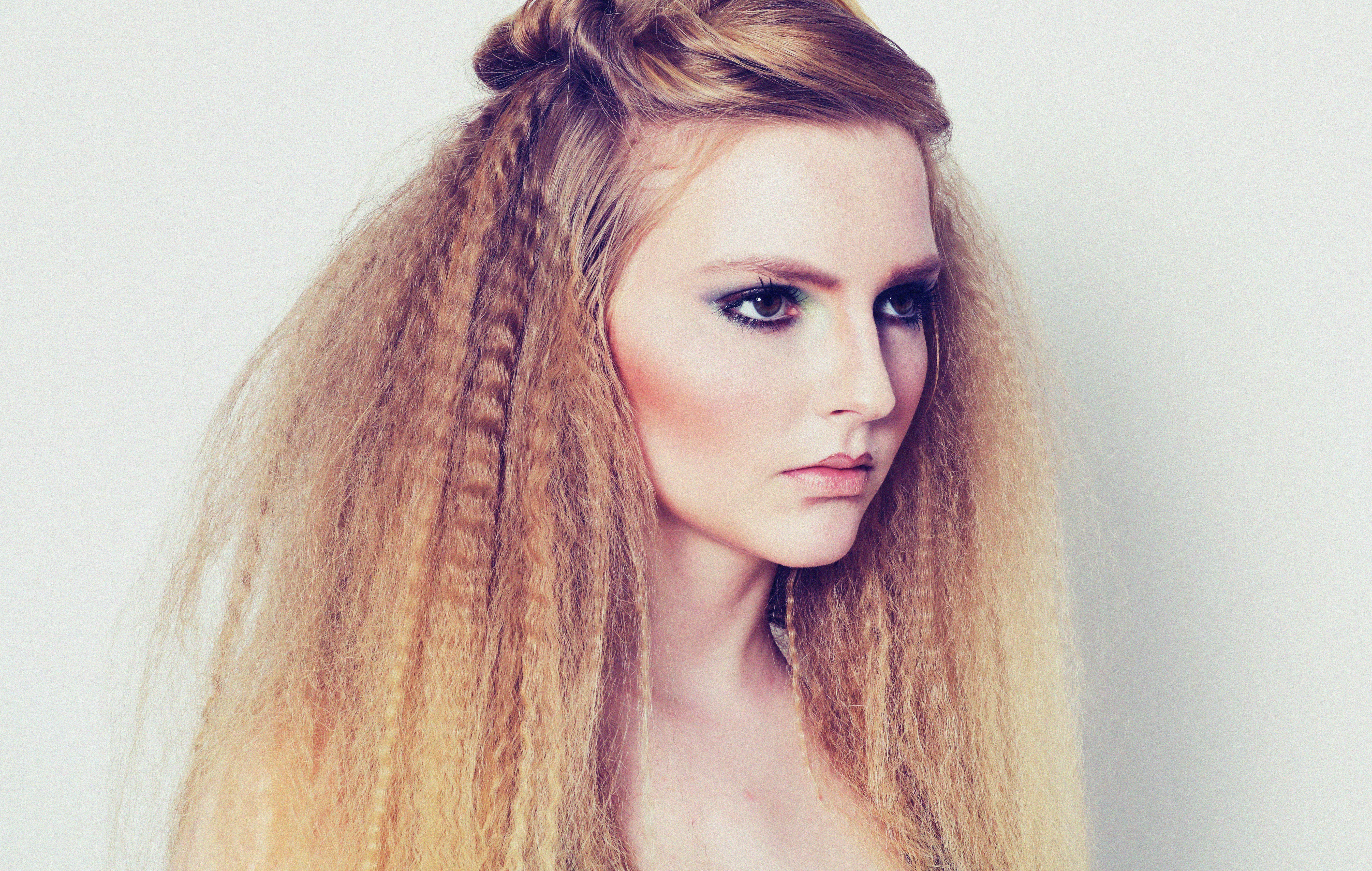 A woman with long crimped blonde hair and dark eye makeup
