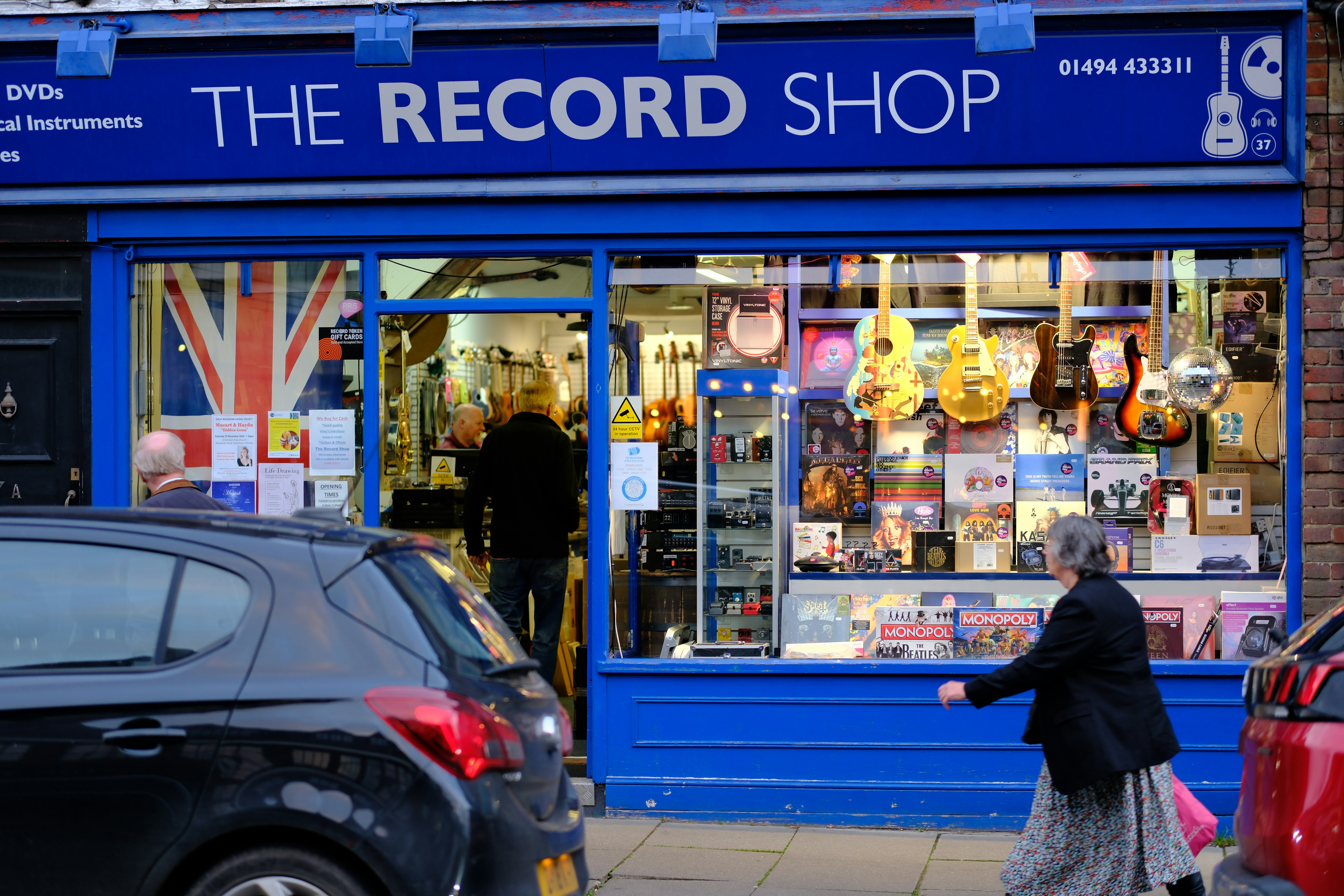A blue storefront with a sign reading "THE RECORD SHOP" displaying guitars and vinyl records