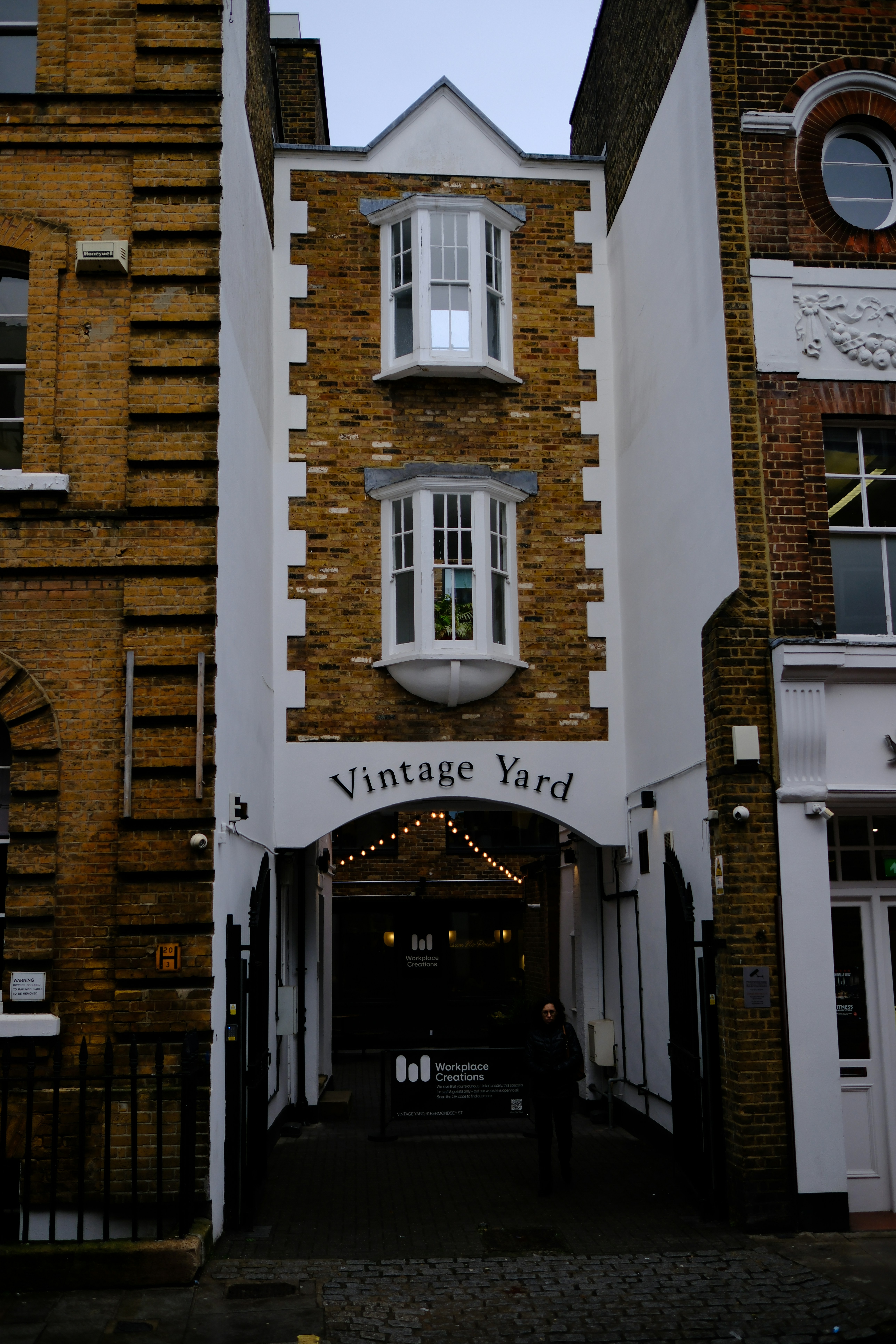 A person walking through the brick archway of Vintage Yard in London