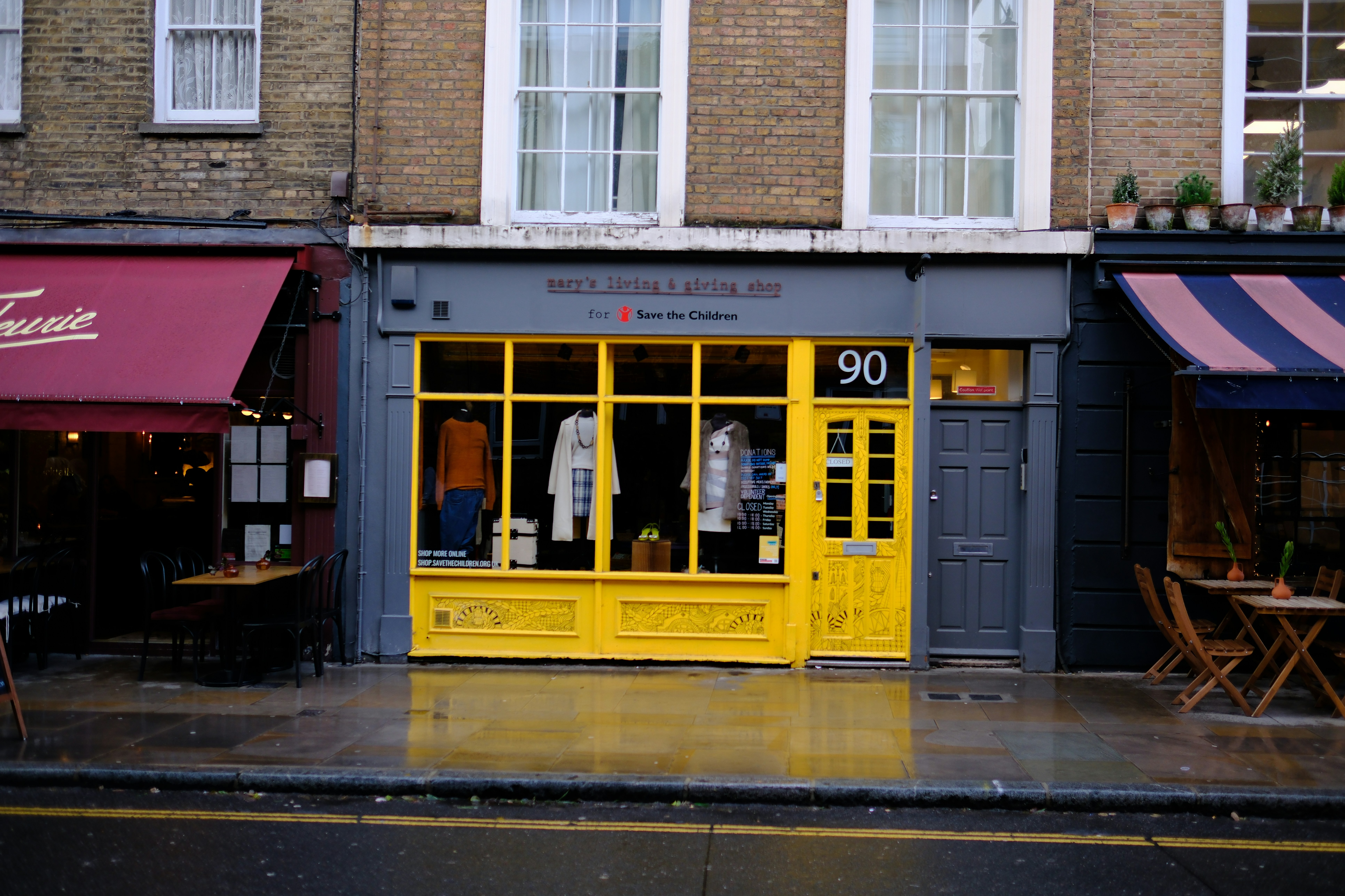 A yellow storefront with a clothing display in a brick building on a street