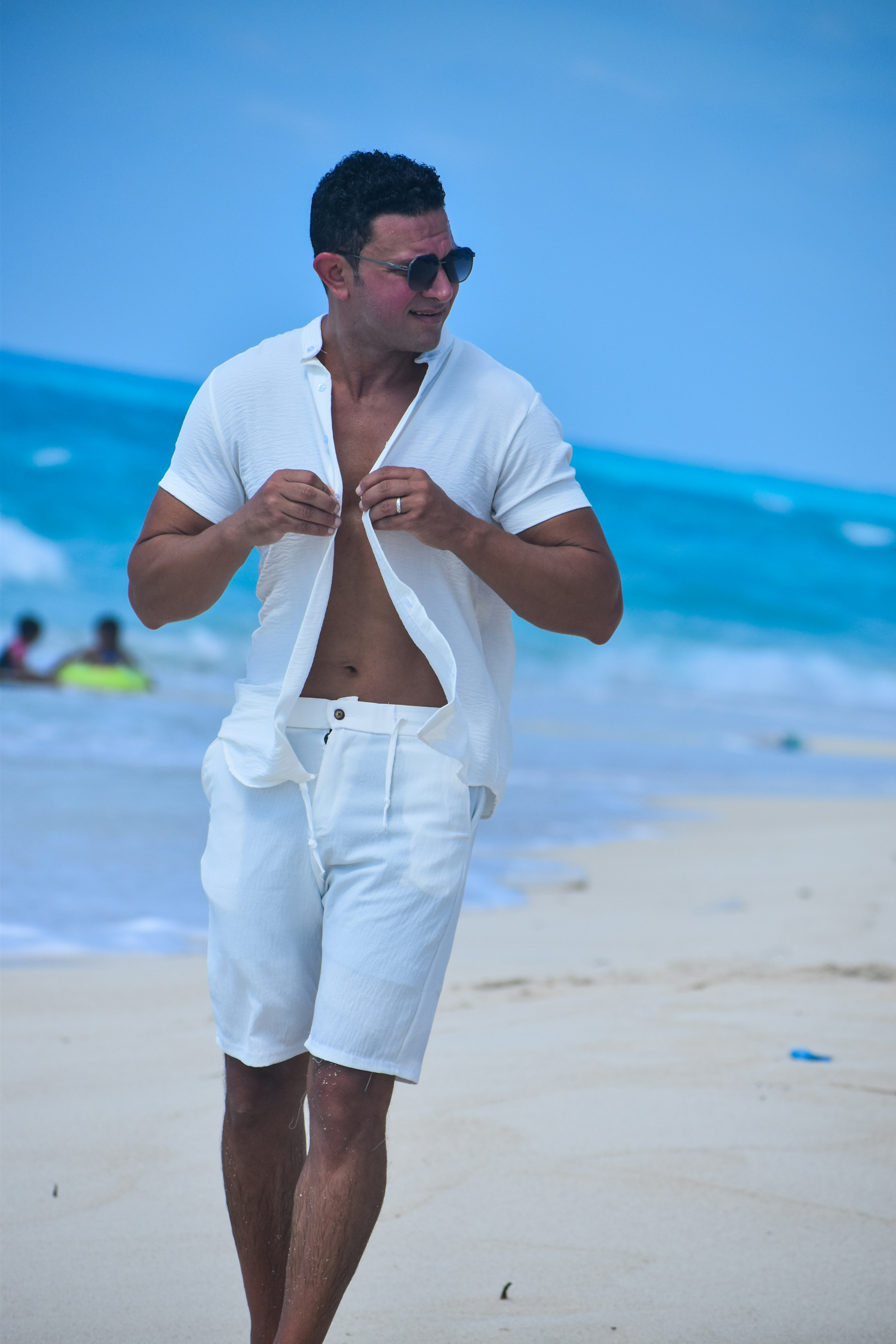 Hombre con camisa blanca caminando por la playa