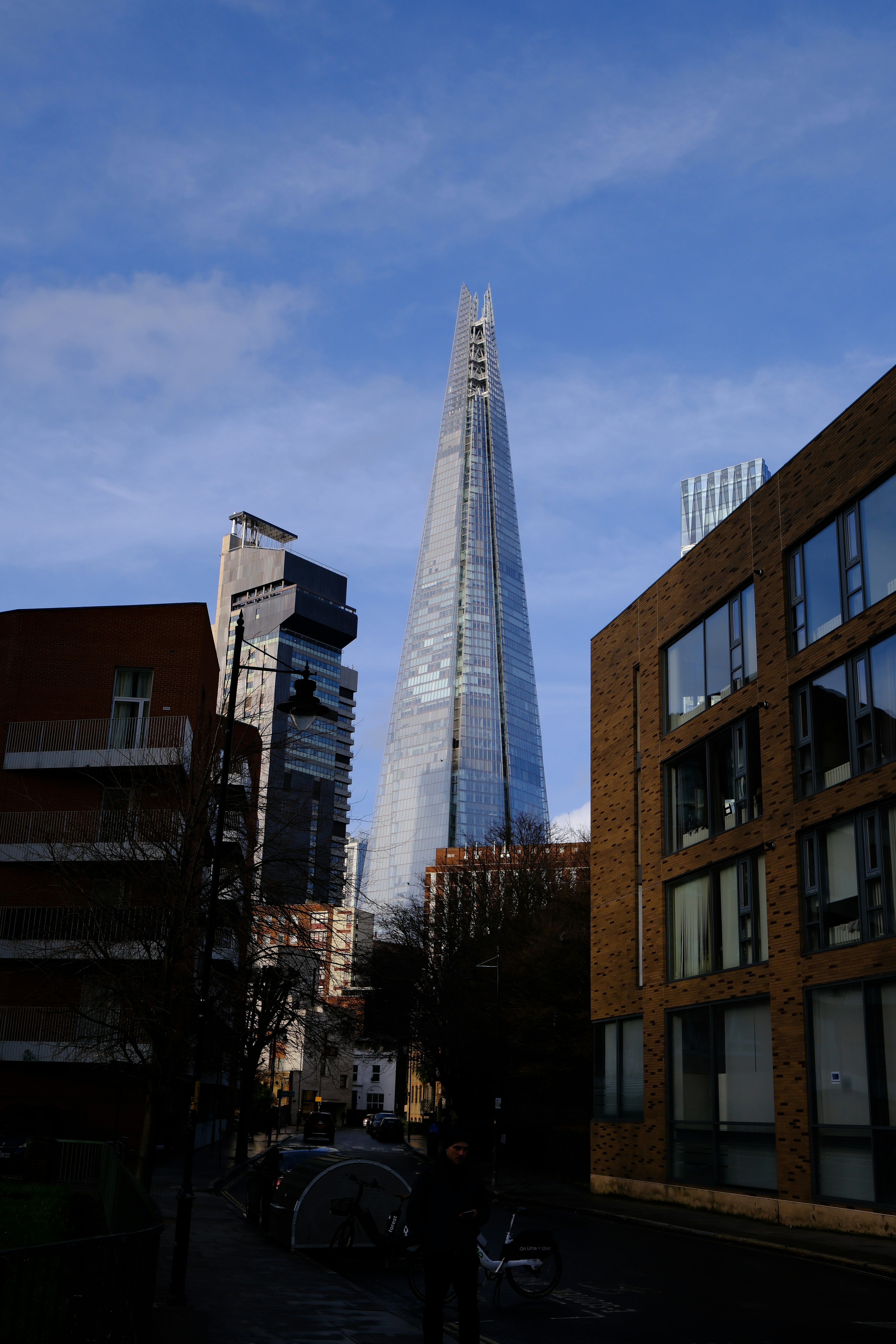 The Shard skyscraper rising above urban buildings in London under a blue sky