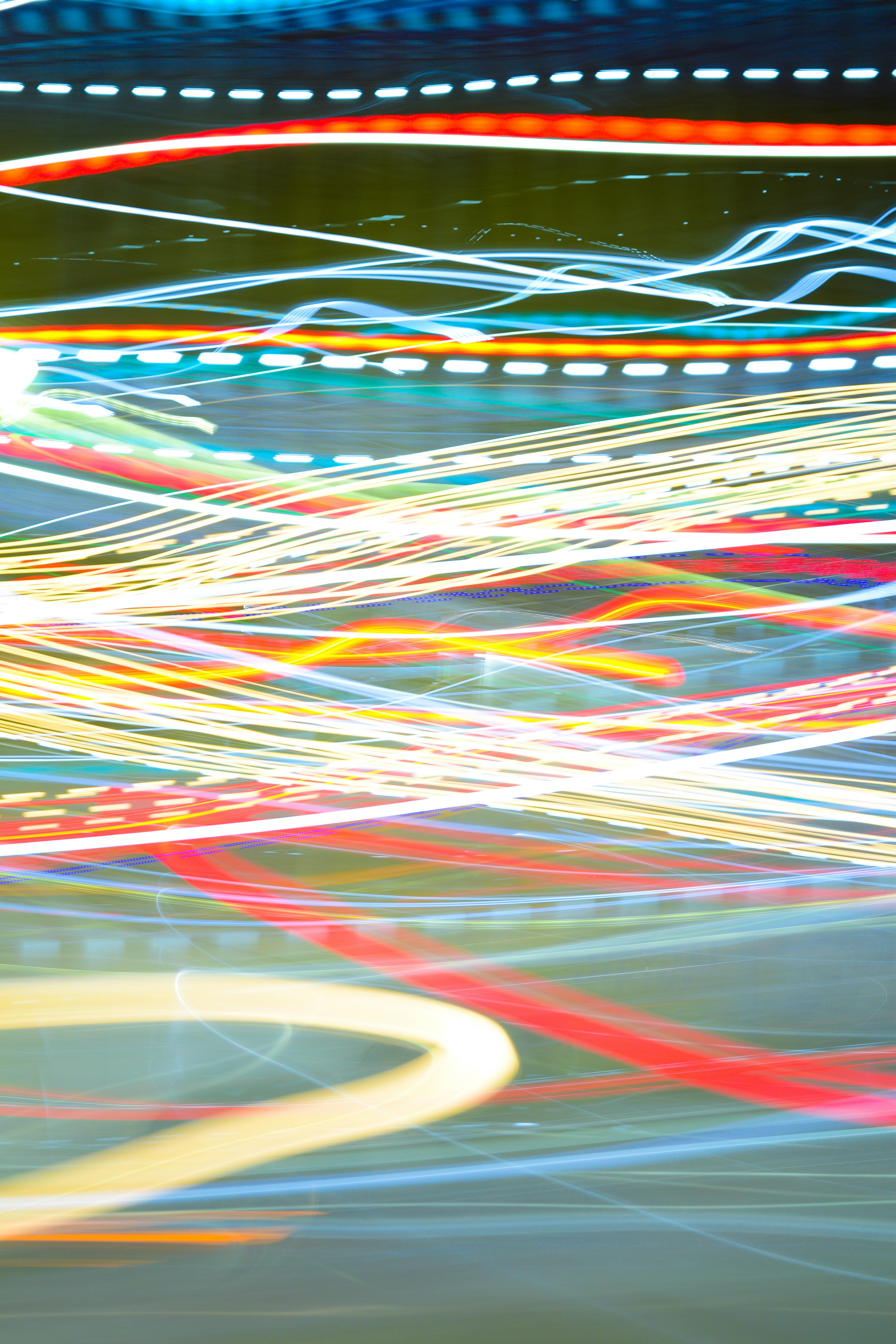 Long exposure light trails in red, yellow, and blue against a dark background