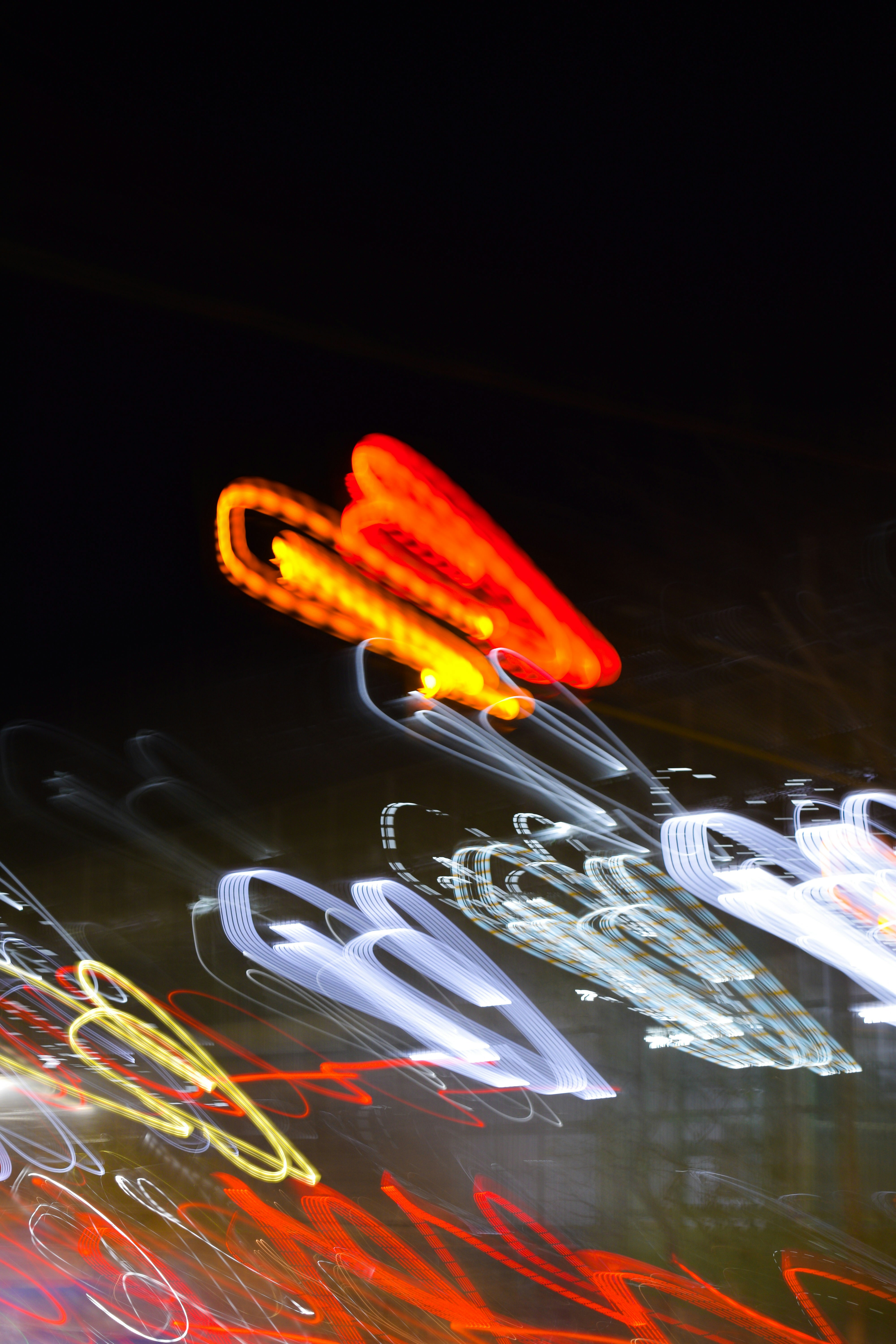 Long exposure light trails in red, yellow, and white against a black background