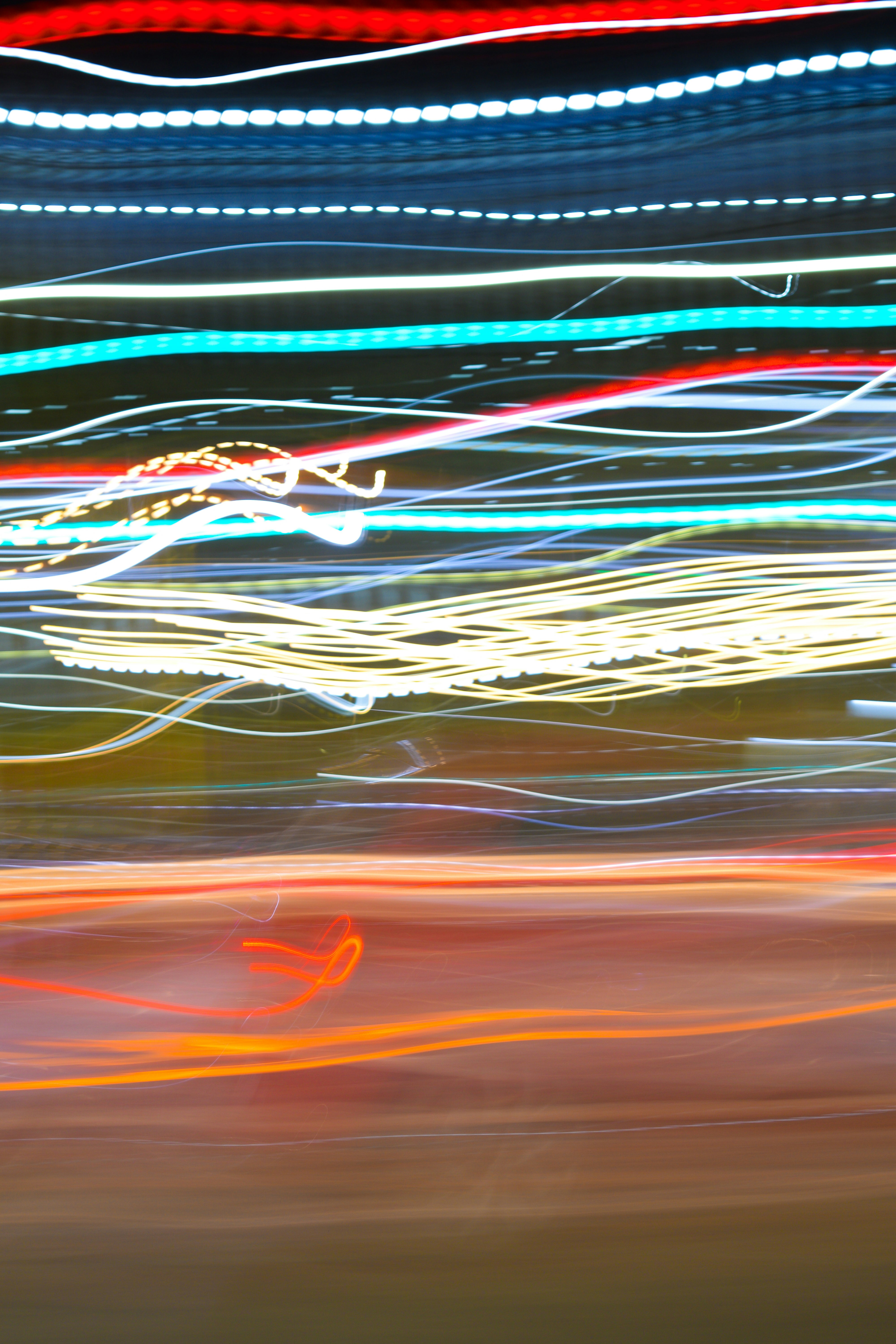Long exposure light trails in blue, yellow, and red across a dark background