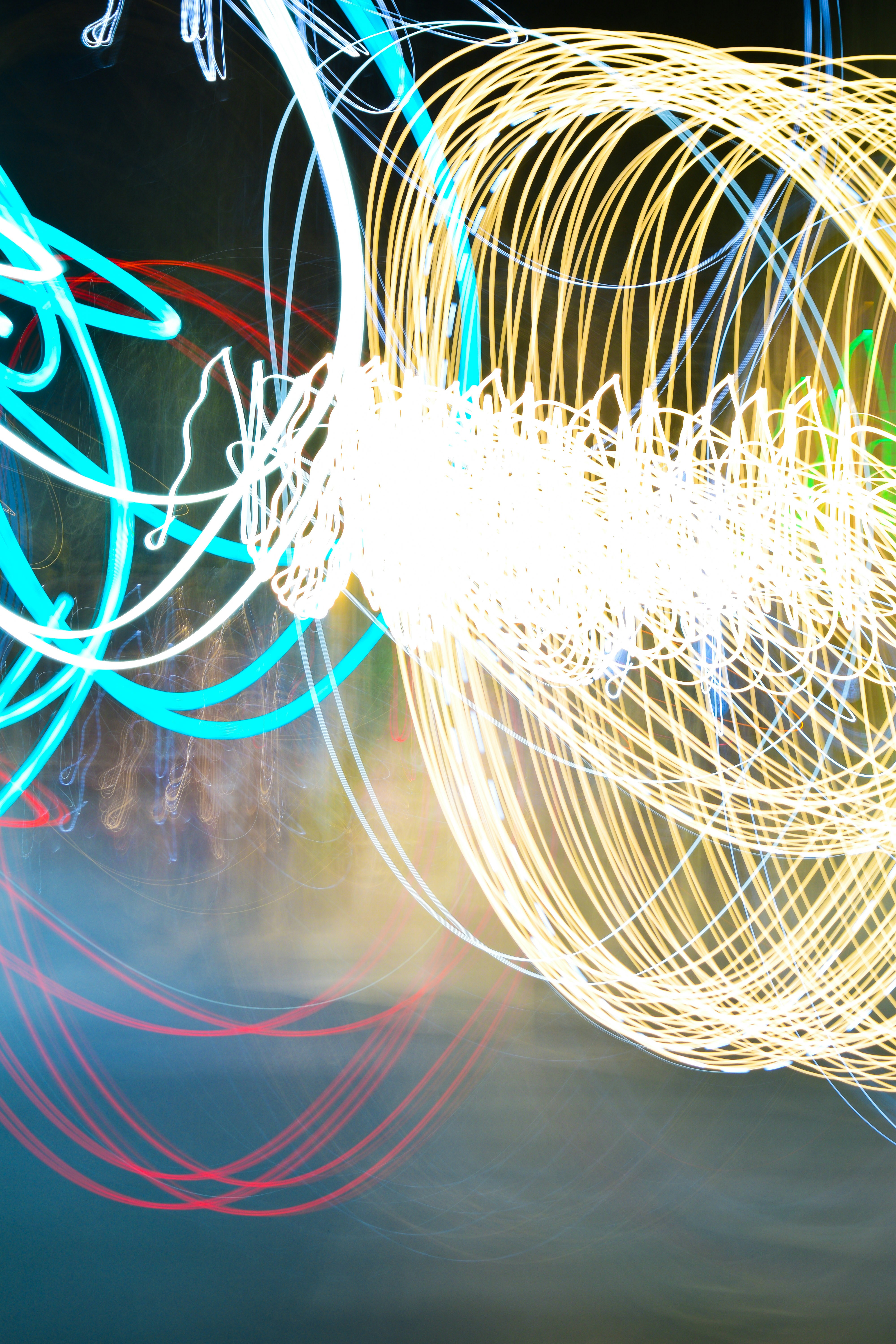 Long exposure light trails in blue, yellow, and red against a dark background