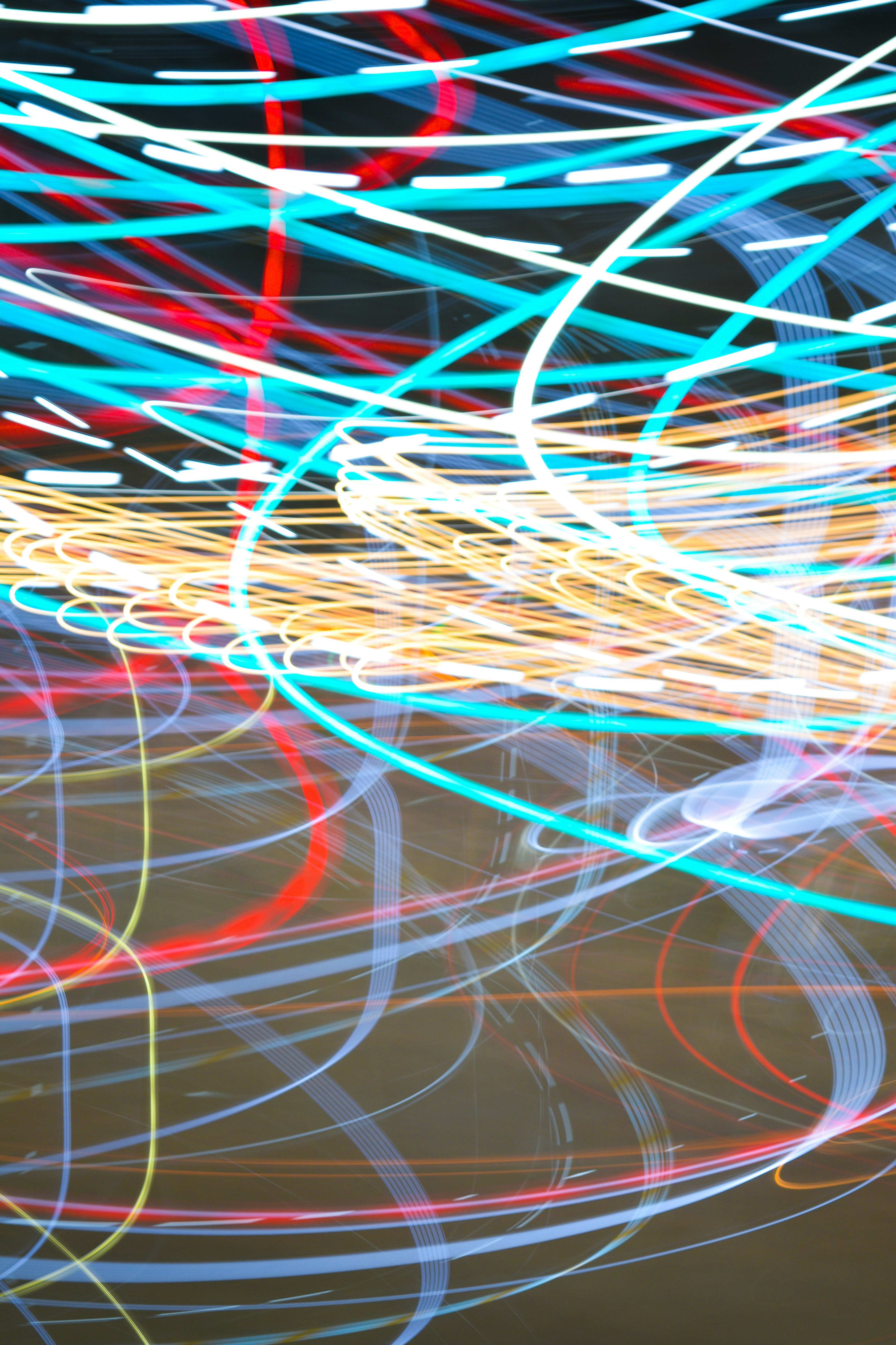 Long exposure light trails in vibrant shades of cyan, red, and yellow