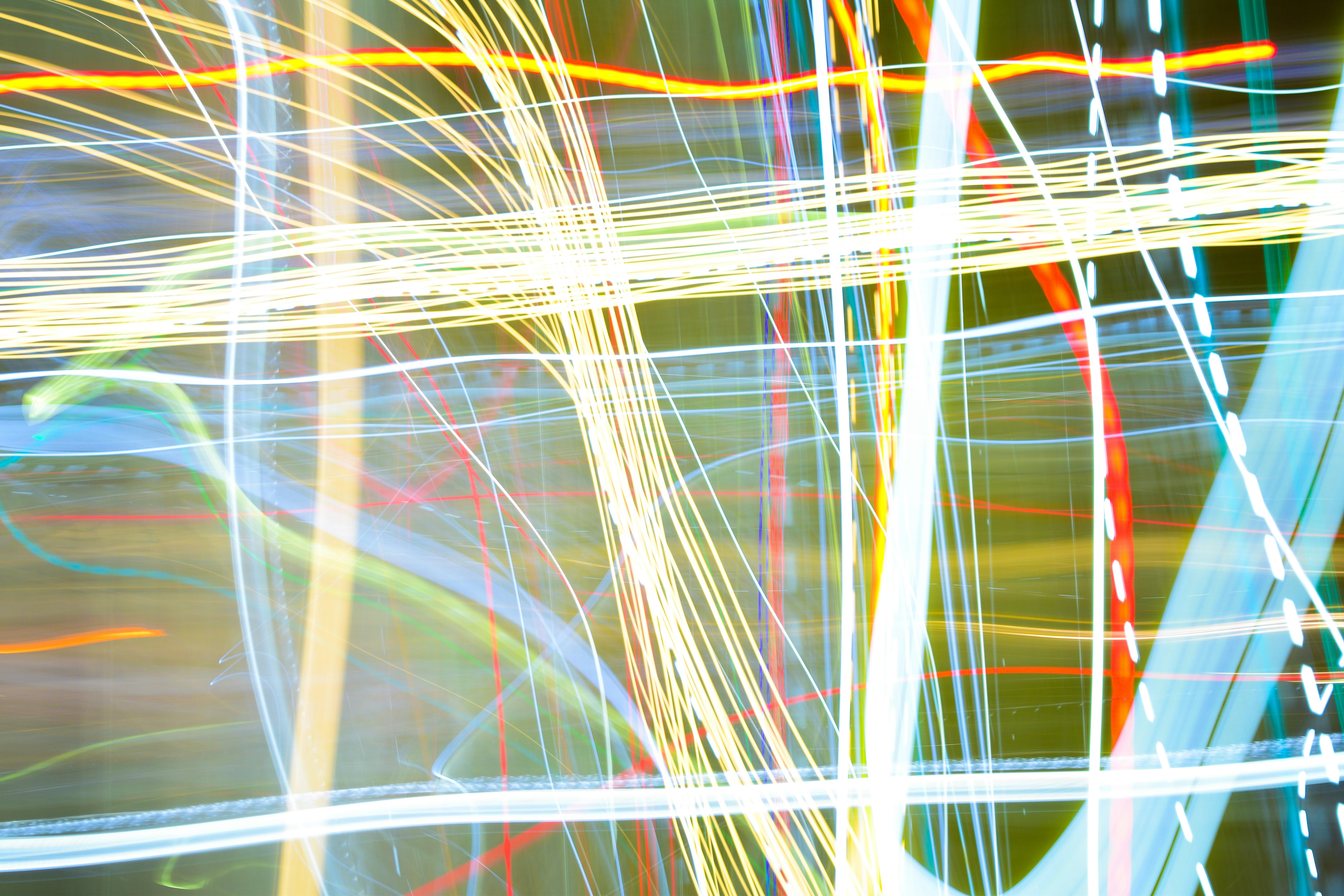 Long exposure light trails in yellow, red, and blue against a dark background