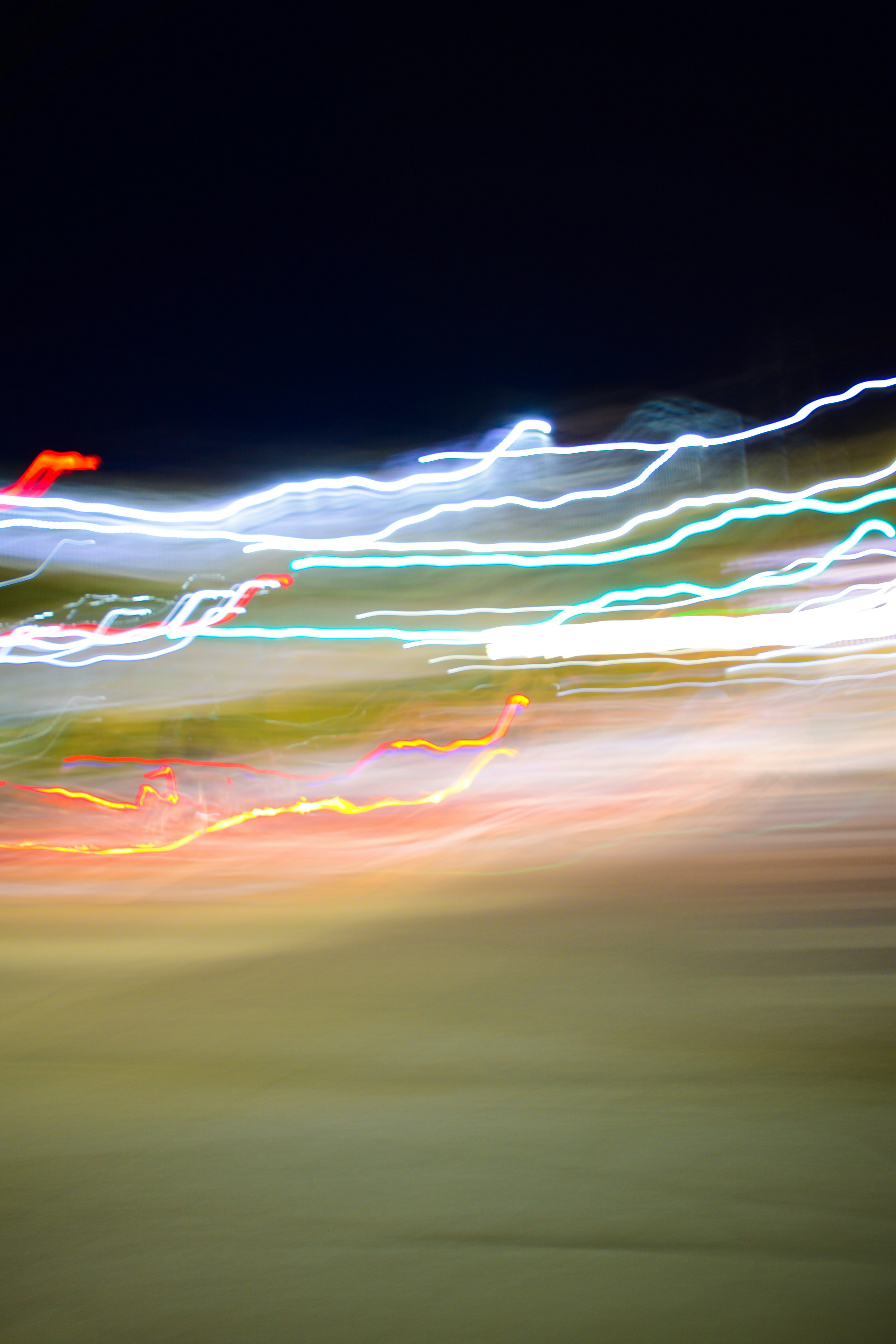 Long exposure light trails in white, blue, and red against a dark background