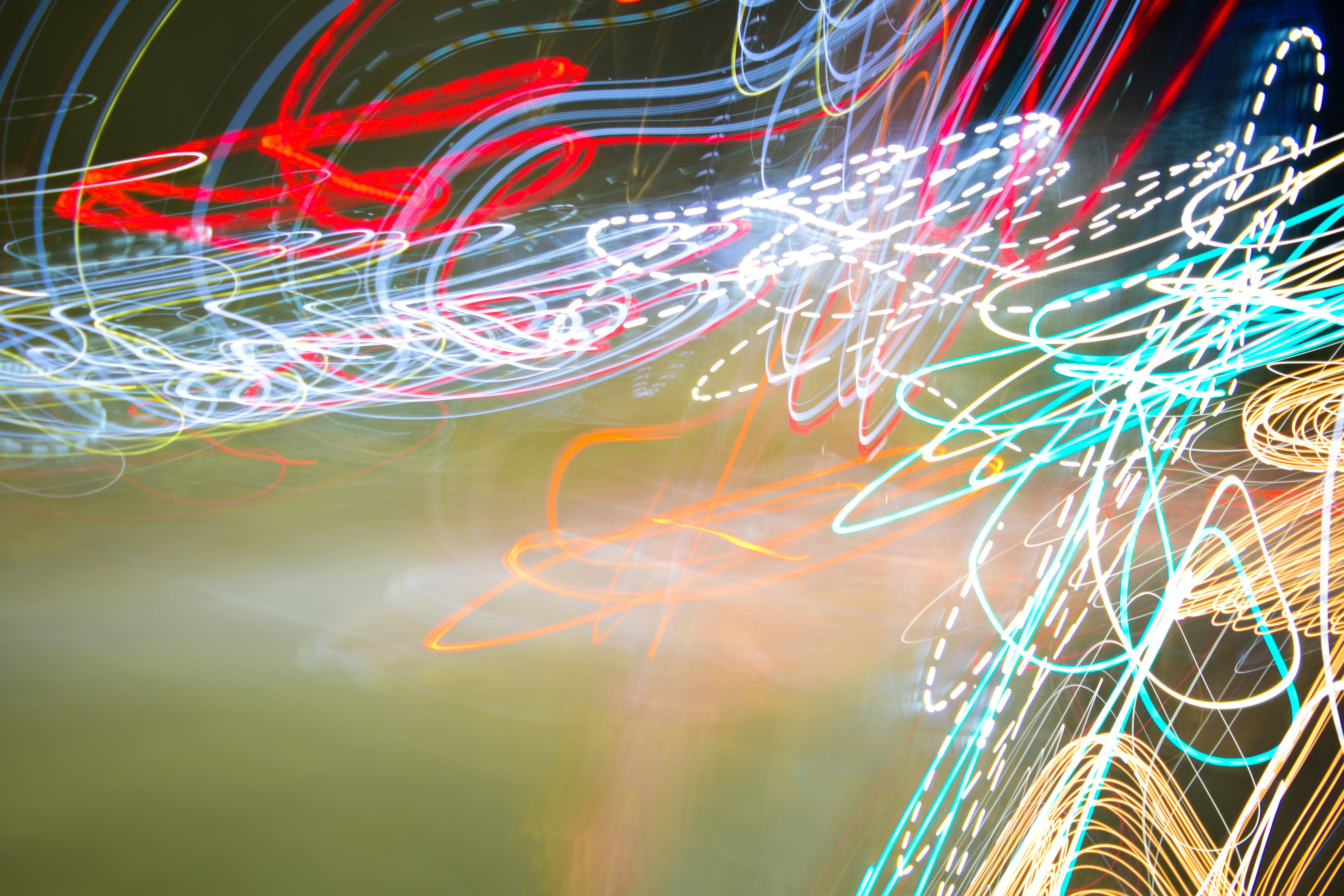 Long exposure light trails in red, white, and blue against a dark background
