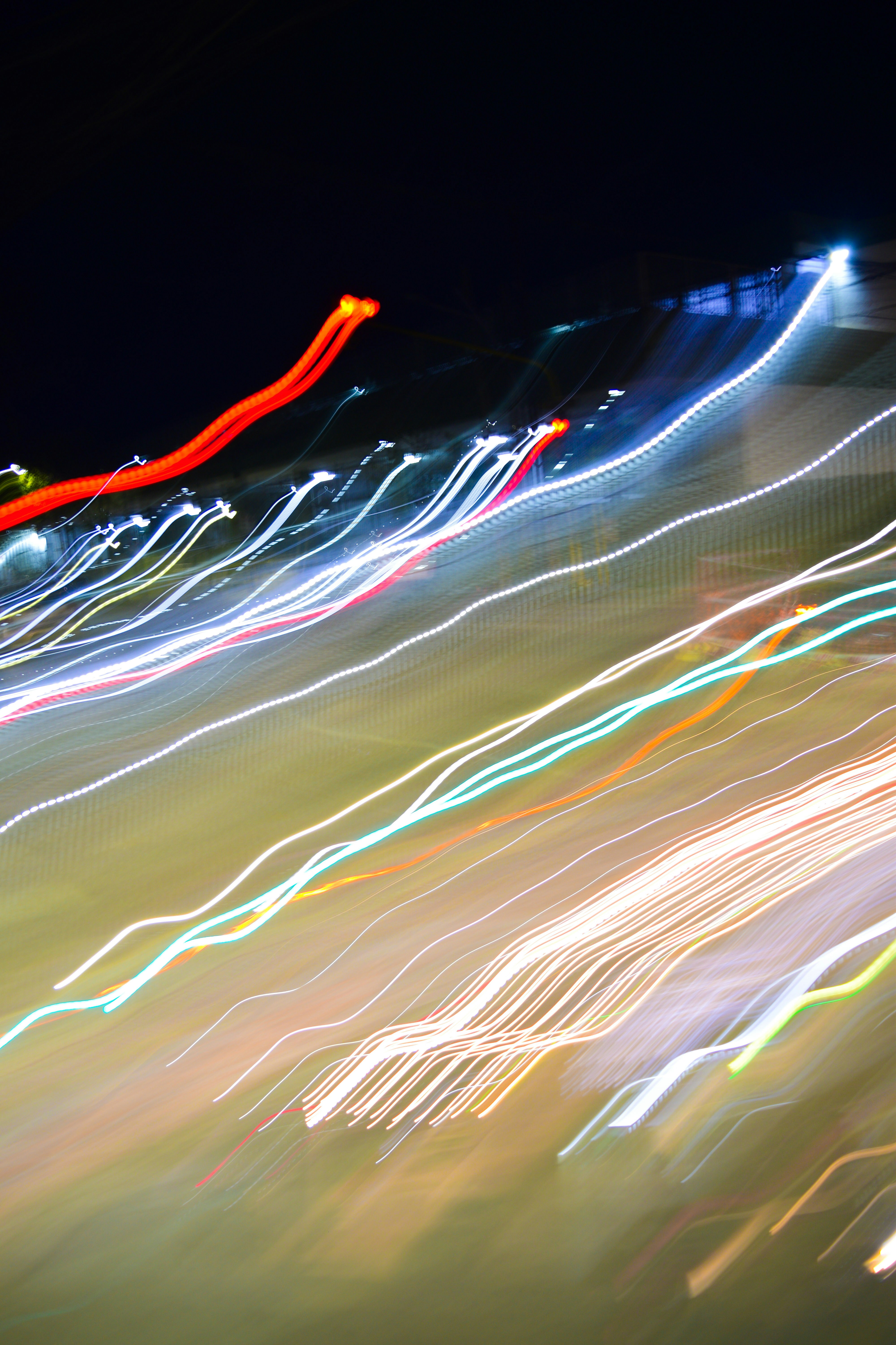 Long exposure light trails in red, white, and blue against a dark background
