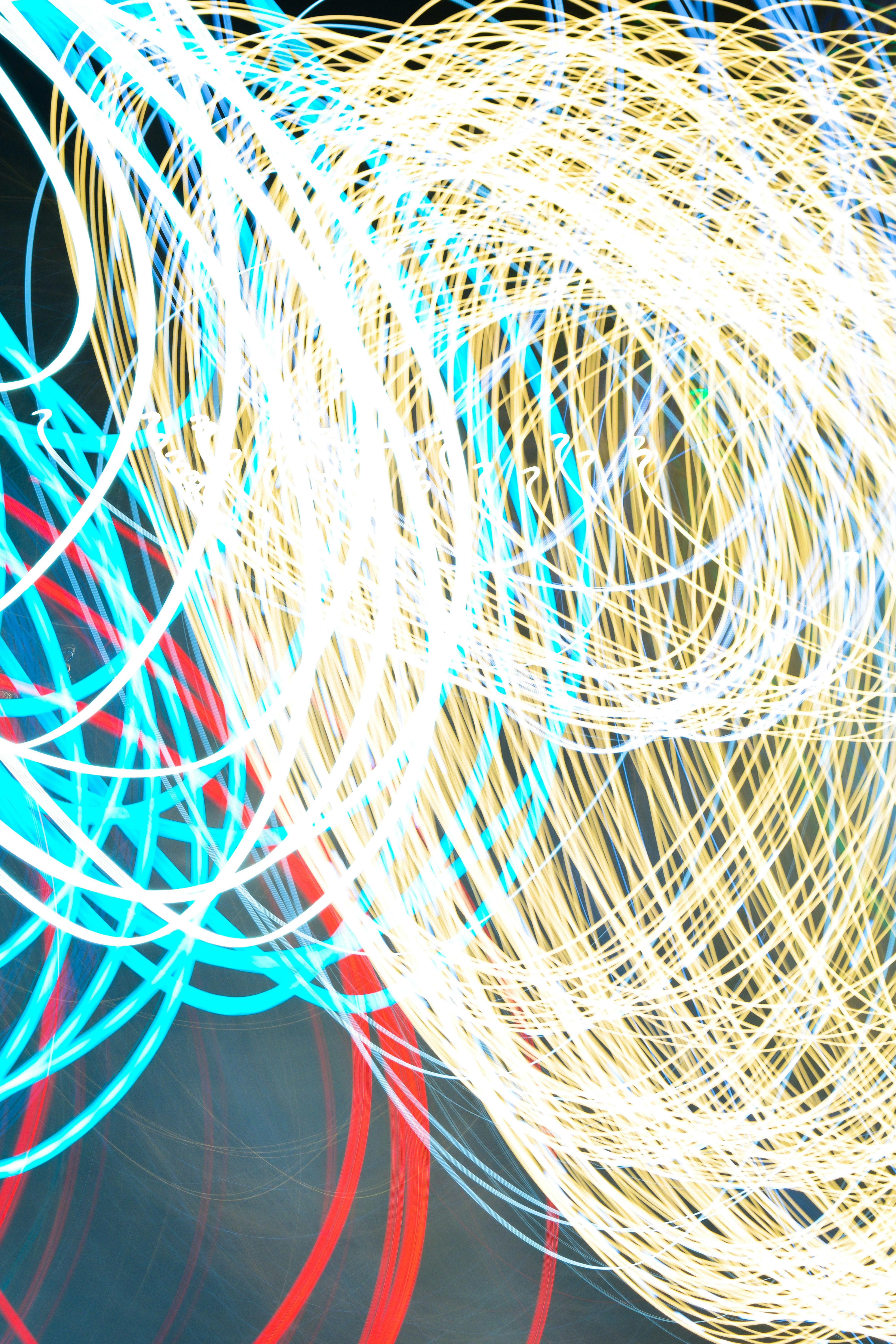 Long exposure light trails in white, cyan, and red against a dark background