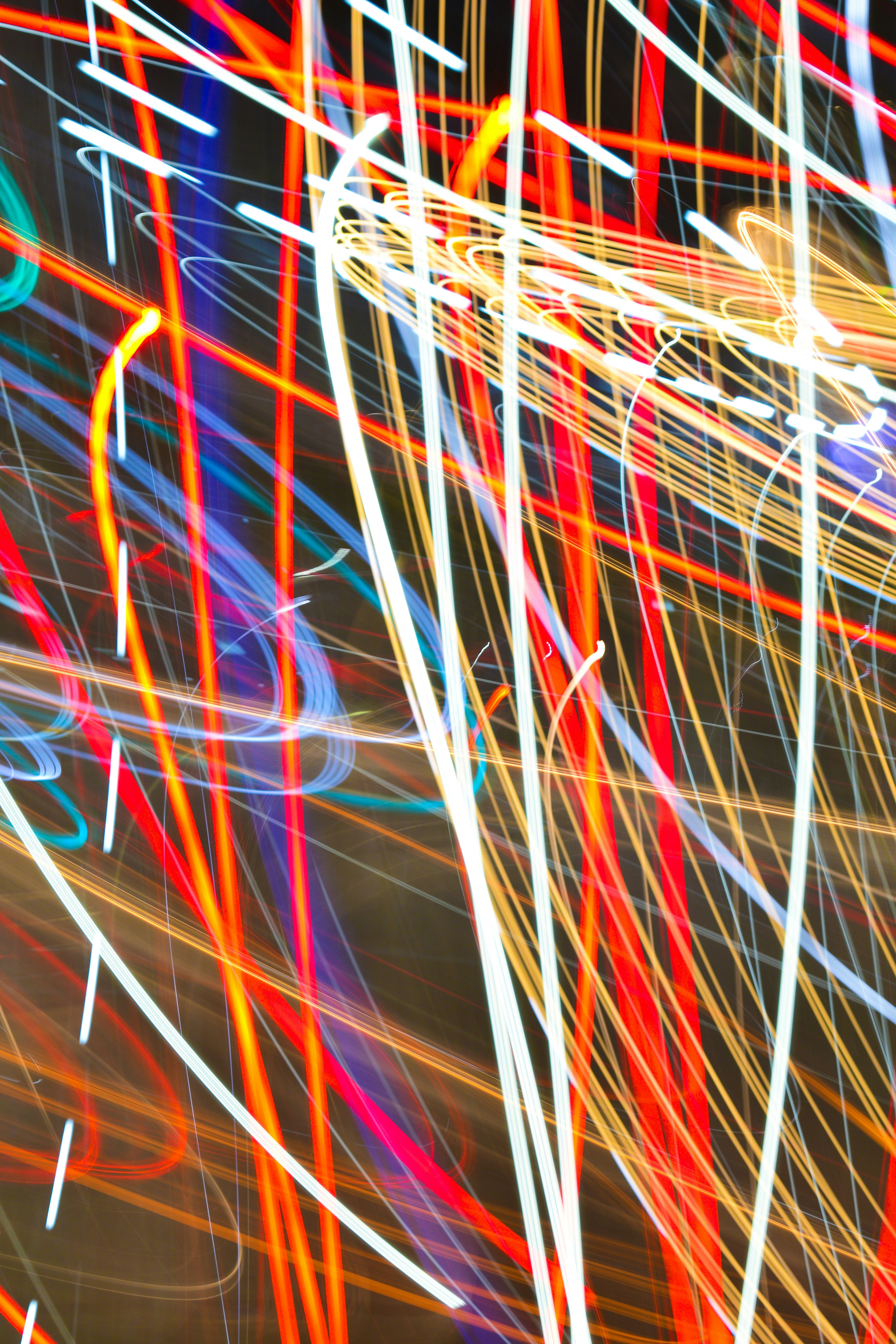 Long exposure light trails in vibrant red, yellow, and blue against a dark background