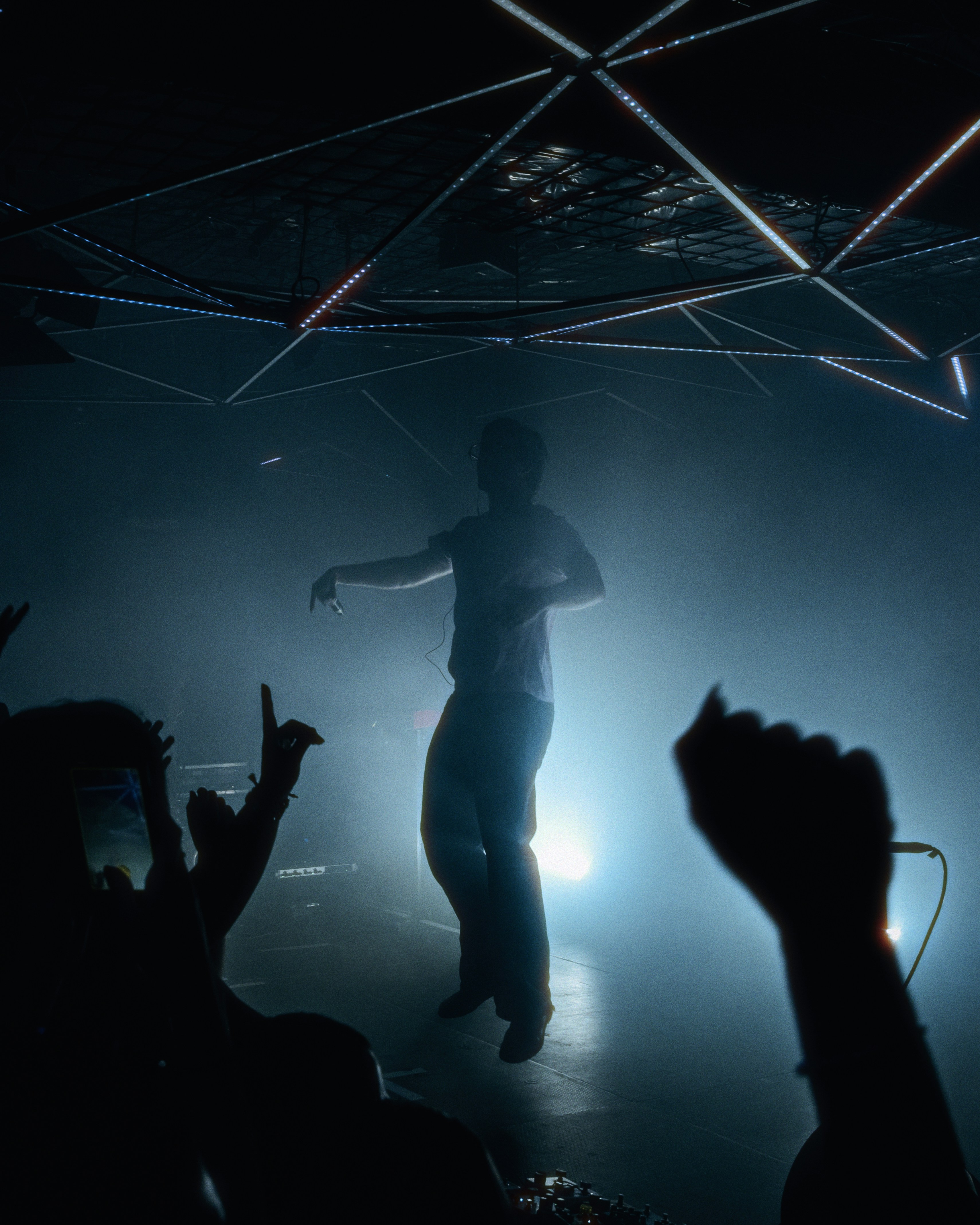 A person dancing on a stage under bright lights in a dark club