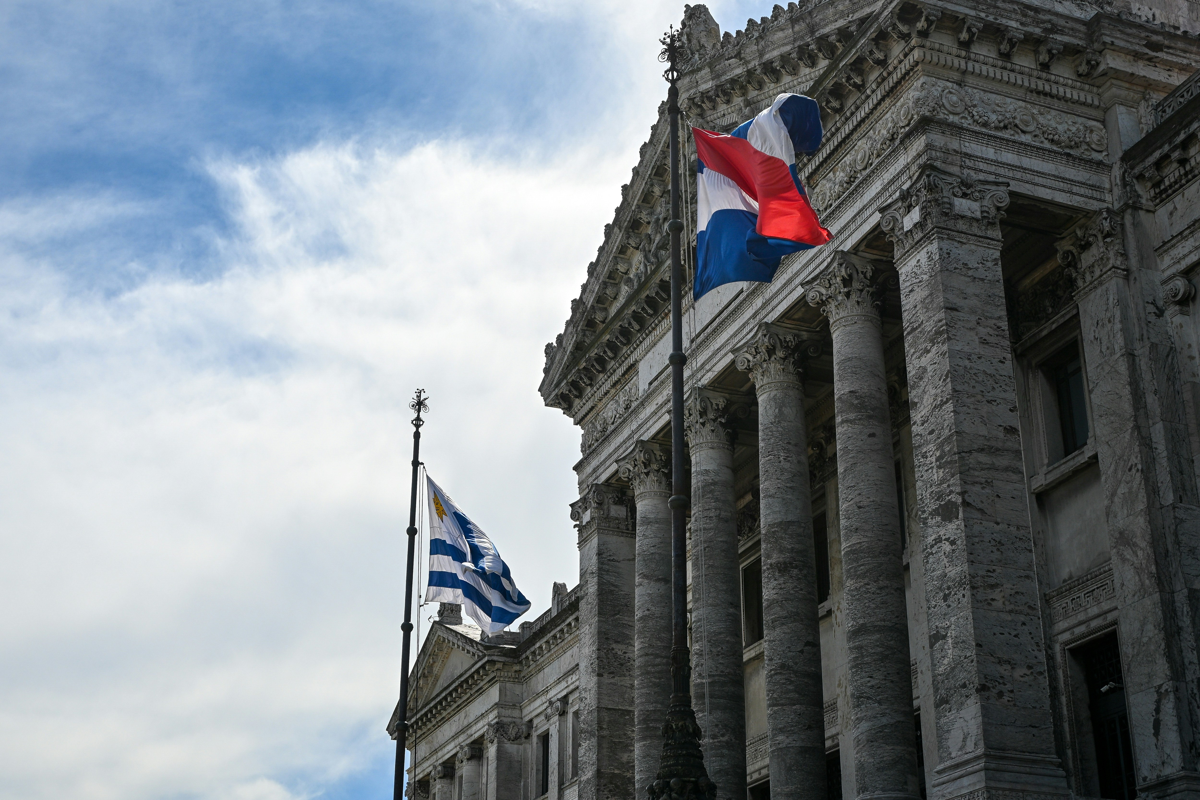 Flags of Uruguay and the Netherlands flying before a neoclassical stone building
