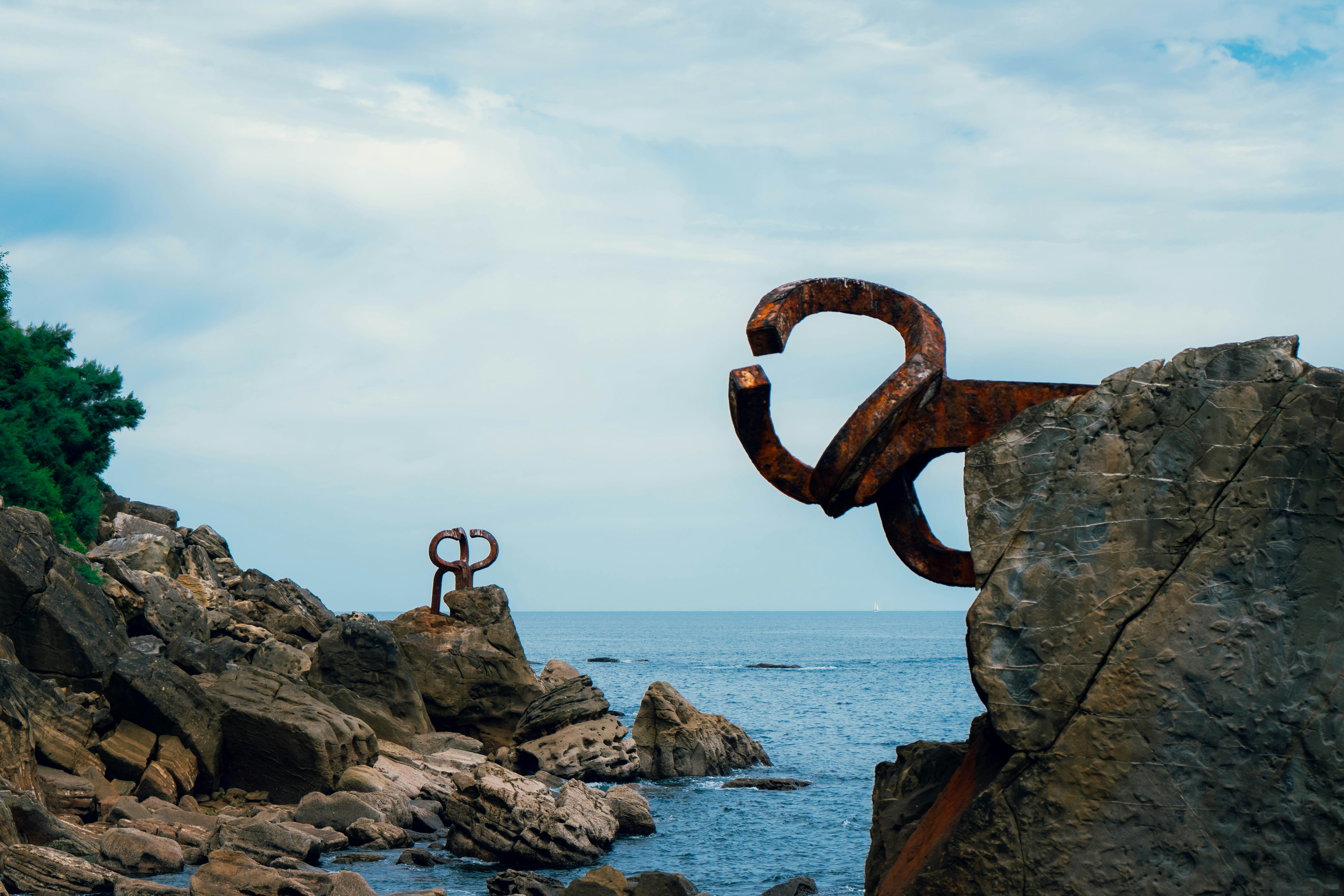 Rusty iron sculptures on rocky cliffs above the sea in San Sebastian