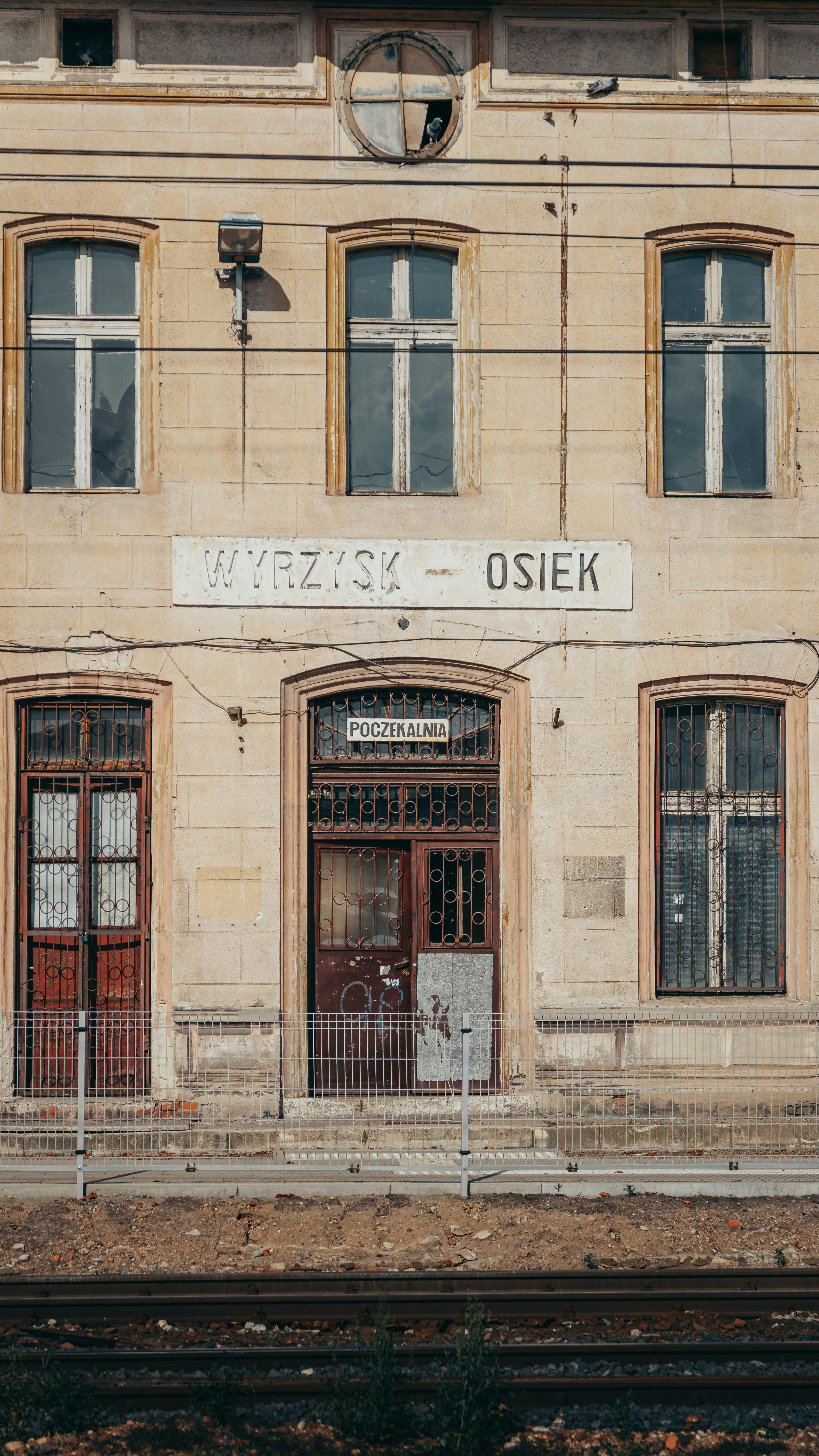 O edifício da estação de trem Wyrzysk-Osiek com fachada desgastada e grades metálicas de segurança