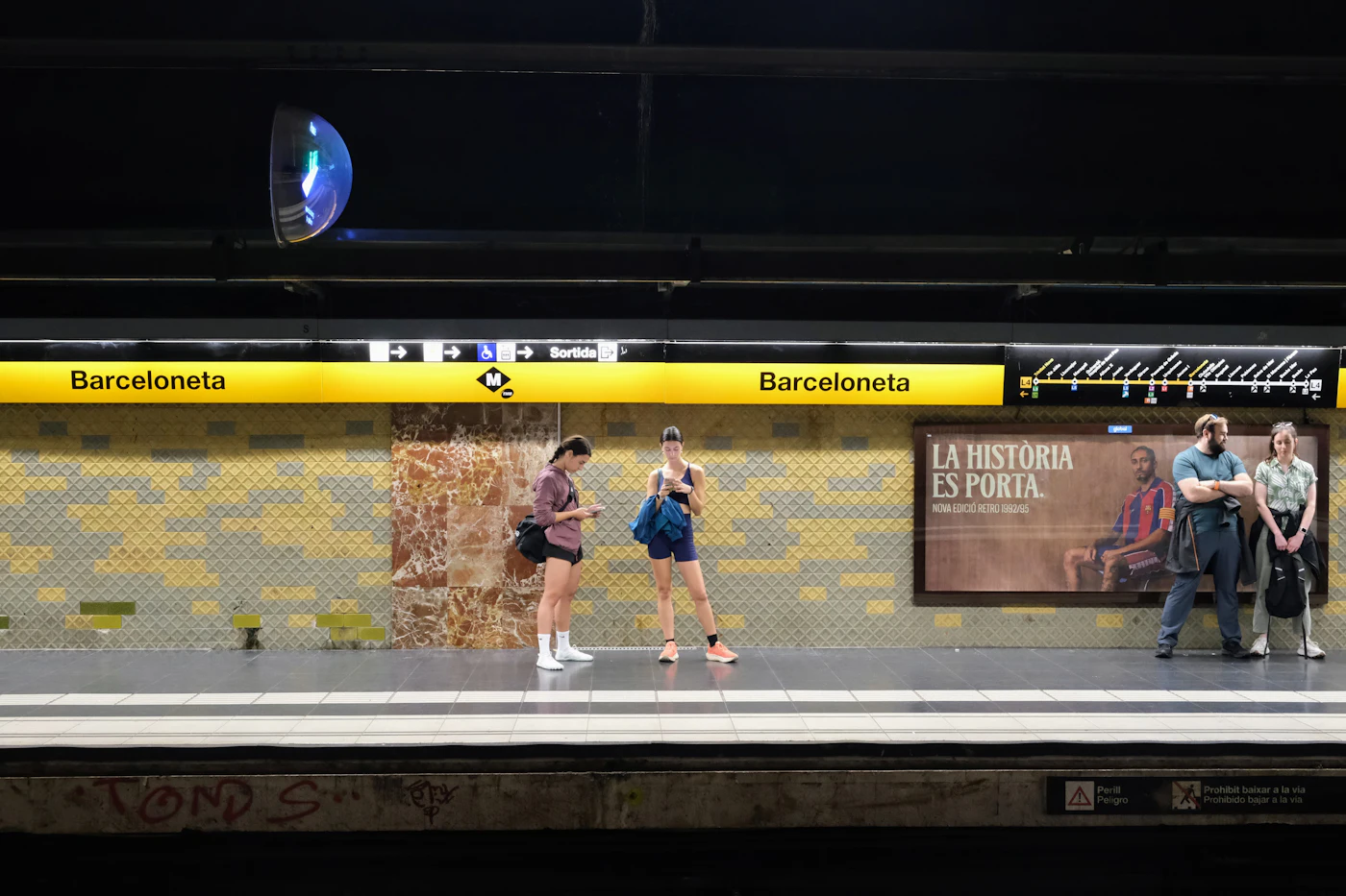Vier reizigers wachten op het perron van metrostation Barceloneta
