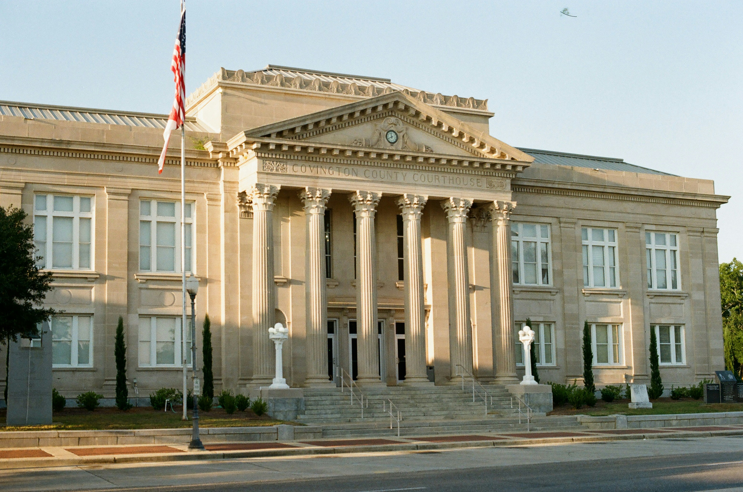 The Covington County Courthouse with neoclassical columns and an American flag in Andalusia