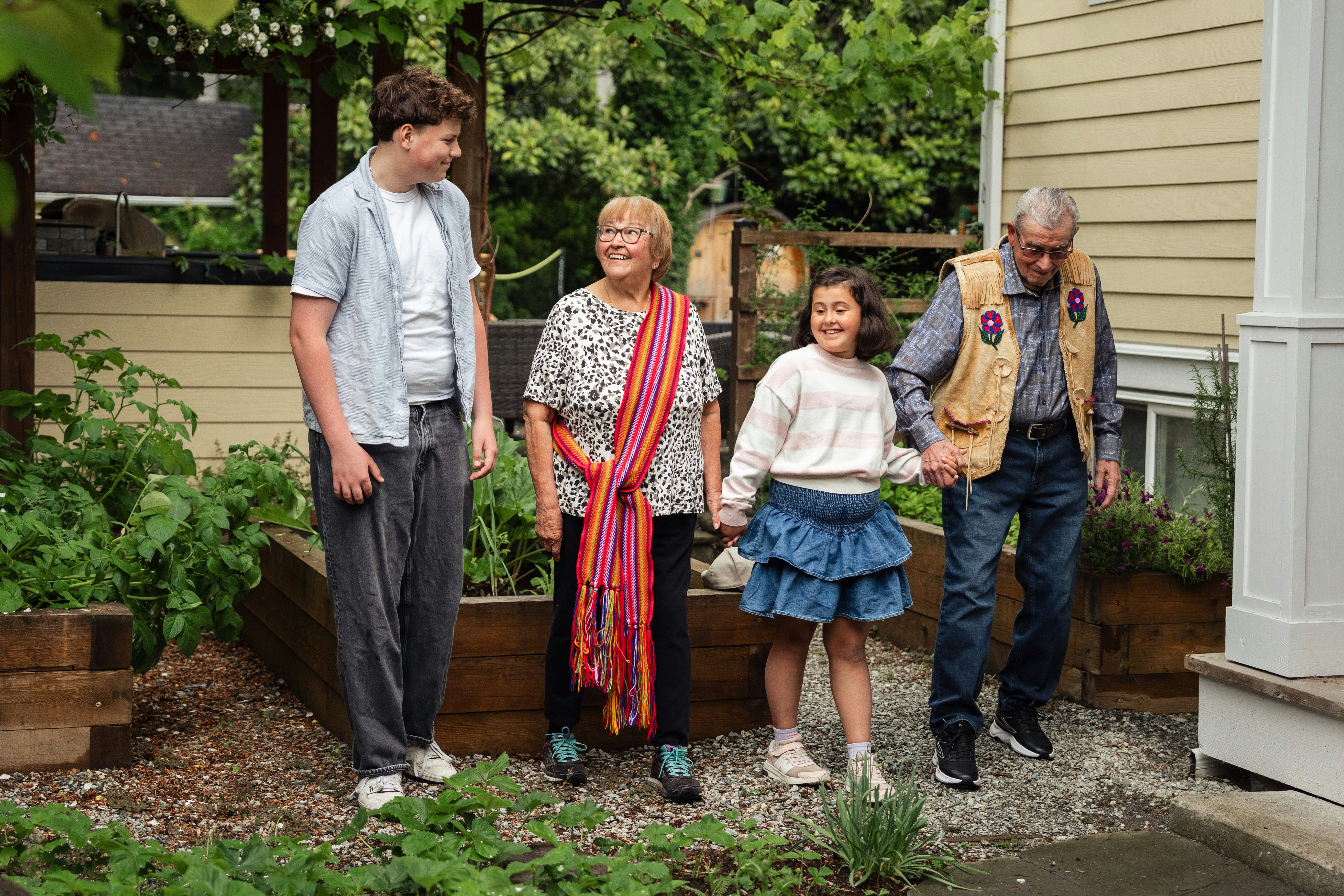 A family walking together through a neighborhood garden beside a house