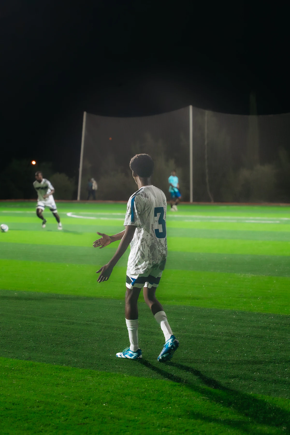 A player waits for the ball on a floodlit 3G pitch