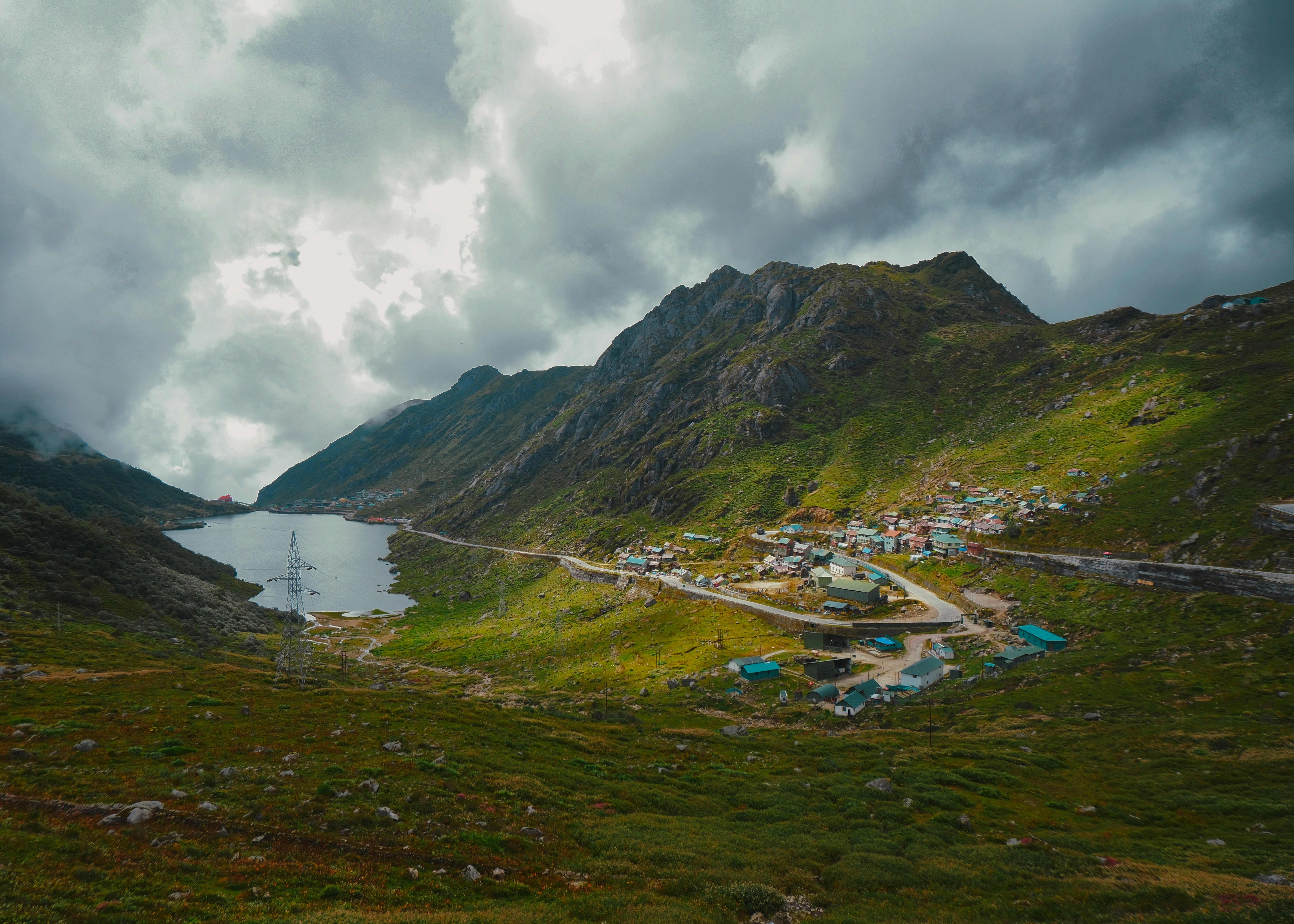 A small village nestled in a green mountain valley beside a dark lake